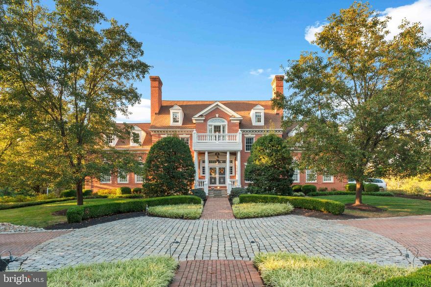 Set amid almost seven acres of beautifully landscaped grounds, this exceptional Southern style Colonial estate embodies timeless elegance, masterful craftsmanship, and a rare sense of character and grace. The property encompasses a stately six bedroom main residence, a charming one bedroom guest cottage, and impressive garage accommodations totaling seven bays, all meticulously maintained and thoughtfully designed for both grand entertaining and everyday comfort.

As you approach the property, an extensive and eye catching cobblestone and brick driveway sets the tone, creating a dramatic first impression and offering a glimpse of the timeless beauty that awaits beyond.

From the moment you arrive, the home’s classic façade and extensive millwork hint at the refinement within. Step through the front door and be greeted by a sweeping staircase and a foyer that immediately conveys the home’s extraordinary quality. Every inch reflects superior craftsmanship, from the beautiful oak floors to the dentil and crown moldings, wainscoting, and custom woodwork found throughout.

A richly appointed office with intricate millwork, custom built-ins and a wood burning fireplace with marble surround provides an inspiring workspace, while the banquet sized dining room is ideal for elegant gatherings. The heart of the home is the remarkable great room, an architectural showpiece with massive exposed beams, cathedral ceilings, a dramatic floor to ceiling fieldstone fireplace, and gleaming Brazilian cherry floors. French doors open to a large screened porch, perfect for relaxed seasonal dining or quiet evenings overlooking the lush landscape.

The chef’s eat-in kitchen is a true standout, both stylish and functional, featuring custom cabinetry, granite countertops, and professional grade stainless steel appliances including a Wolf commercial gas cooktop with electronic display, dual Wolf convection ovens, over-sized refrigerator, and walk in pantry.

The primary suite, beautifully remodeled in 2024, offers a serene retreat with two closets, a walk in closets and a custom designed built-ins, a private laundry room with dual washers and dryers, and a luxurious spa bath with a whirlpool tub and exquisitely tiled shower. Five additional bedrooms and well appointed bathrooms provide space for family and guests alike spread out on 2 floors.

The daylight lower level was designed for entertaining, complete with a kitchenette with quartz countertops, a powder room, and a cozy wood burning fireplace. French doors lead out to a covered brick patio overlooking the heated in ground pool and spa, surrounded by terraced walkways, hardscaping, and mature plantings, creating a private outdoor sanctuary.

The guest cottage is equally inviting, featuring vaulted ceilings, wood floors, a full cherry kitchen with banquette, a spacious bedroom with skylit ceramic bath boasting a clawfoot tub and mosaic tile floor, plus an additional full bath and laundry on the entry level.

Every detail of this property has been carefully considered, from the extensive exterior trim work and PVC crown molding to custom window treatments in every bedroom and a whole home diesel generator serving both the main house and guest cottage. A stately brick walkway leads through enchanting gardens and mature trees, creating an atmosphere of privacy and tranquility rarely found today.

Ideally located near fine dining, shopping, and scenic state parks, with easy access to I 95, this remarkable estate blends classic Southern charm with refined modern living. Exuding warmth, craftsmanship, and enduring beauty, this is a home that must be experienced to truly be appreciated.