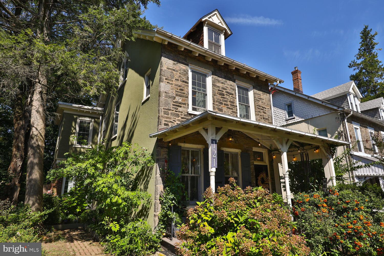 The magic of Mt Airy abounds in this heart stopping, Victorian stone single. Though the iron gate and past the front, lush garden you'll walk up the steps to the welcoming, comfy porch perfect for enjoying your morning coffee, cuddling up with a book, or just displaying your favorite seasonal decorations. Inside and through the vestibule is a lovely open concept living and dining room with tons of windows and light and random width pumpkin pine floors.  A country-style kitchen is beyond this, leading to a 3 season family room addition. From here you can step out onto the wide deck, great for entertaining, and look out onto your massive backyard with  multiple gathering spaces, a multitude of garden areas, an outdoor fireplace, a shed that could be used as a chicken coop that has an attached fenced in run, an old but renovated building that was once a summer kitchen and now could be used as a studio, storage space, workshop, etc and areas for relaxation and for play. Upstairs you'll find three beautiful bedrooms and beautifully tiled full bath on the 2nd floor. The third floor is a large open bedroom with ornate, original leaded glass windows offering tons of beautiful light and  a number of of charming closet nooks for ample storage.. The basement is clean, dry, and freshly parged for great storage and laundry, with easy stairs and bilko doors that give access to the side yard. There is a two car driveway for off street parking.
Showings start on Saturday 9/23