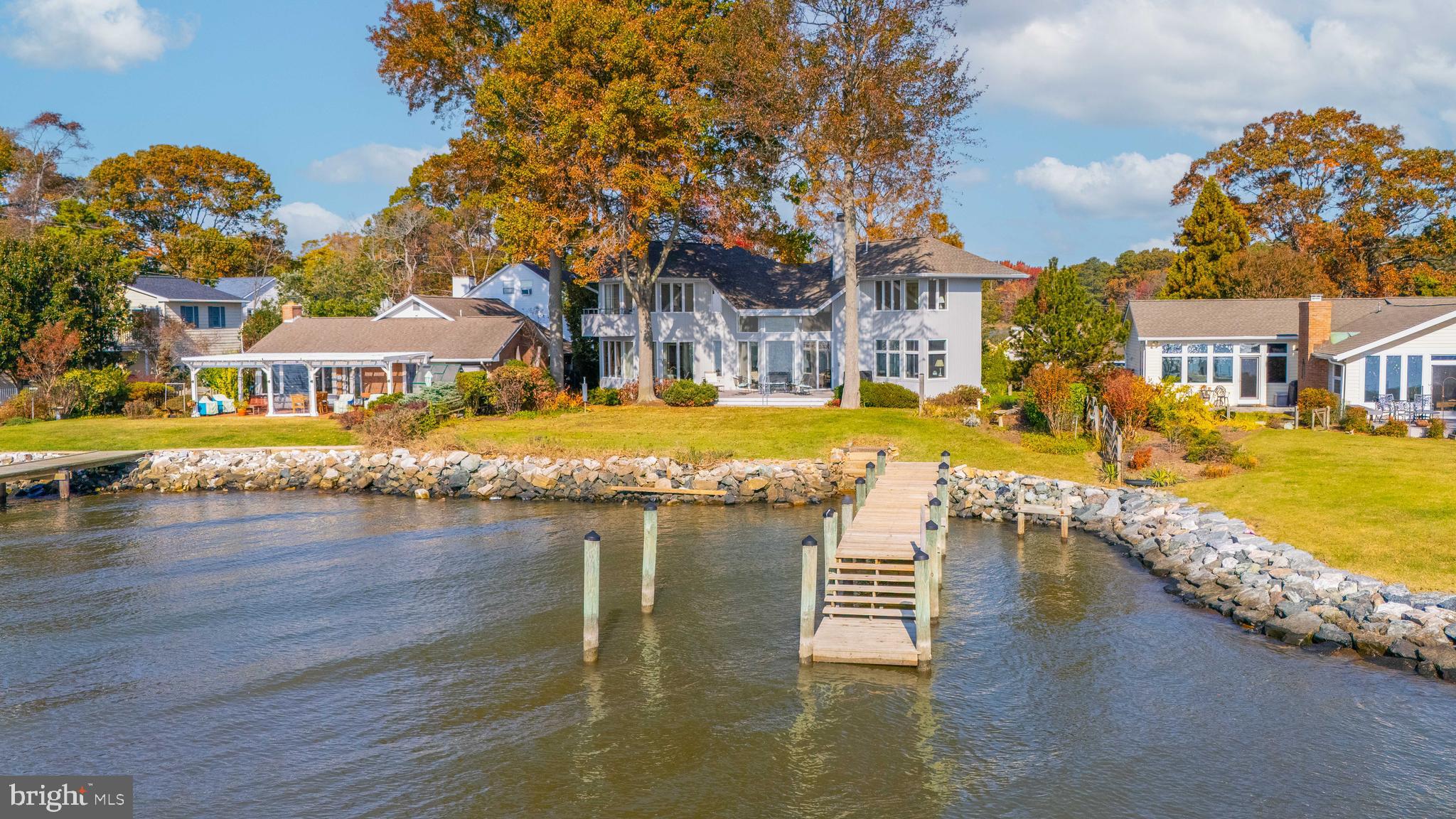 This remarkable custom-built waterfront home offers breathtaking, expansive views of the Chesapeake Bay and its surrounding wetlands. Thoughtfully designed from the ground up, this property showcases stunning vistas from nearly every room, immersing residents in the beauty of the Bay year-round.
The living room is a true centerpiece, with 8-foot sliding glass doors that provide a seamless connection to the outdoor scenery. A striking floor-to-cathedral ceiling stone fireplace with a cantilevered hearth adds warmth and charm to the space, making it an inviting area to relax. The main house includes four bedrooms, two of which feature en-suite bathrooms, with one conveniently located on the main floor. Oak hardwood floors flow throughout, creating a cohesive and elegant aesthetic. The home includes built-in bookcases, a whole-house sound system, and an intercom, for a blend of convenience and sophistication. Dine formally in the dedicated dining room, or start the day in the breakfast room, where morning sunlight enhances the dining experience. The property’s expansive deck offers an idyllic spot to unwind while overlooking the Bay and a tranquil stone pond with a waterfall. The deck provides the perfect vantage point for appreciating the Bay's natural offerings. Seasonal wildlife sightings include tundra swans in winter, ospreys in summer, and eagles year-round, as well as a variety of other birds and waterfowl.
Beyond the main residence, a detached carriage house adds both function and versatility to the property. The upper floor of the carriage house includes views of Carr’s Creek and the Chesapeake Bay, a full bathroom and Murphy bed for guests. Below is a workshop and utility room, enhancing the property’s practicality. This custom-built waterfront home combines luxurious living with the serene beauty of the Chesapeake Bay, offering an exceptional retreat with the comforts of modern amenities and the charm of timeless architecture. The cherry on top -- a whole house generator!