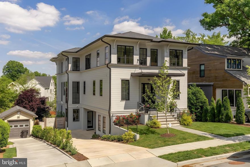 There is new construction in Lyon Park — but there is nothing quite like this.
From the moment you step through the front door, 135 N Edgewood announces itself. A gracious entry foyer opens into a beautiful hallway that draws your eye all the way to the back of the home, where floor to ceiling windows pour light through the entire main level the kind of first impression that stops you mid-step. This is not a house that reveals itself slowly. It lets you see exactly what it is, right away.
The main level is both elegant and livable in equal measure. A dedicated office or flex room sits just off the entry, quietly tucked, completely functional. A powder room. And then the formal dining room, anchored by a designer light fixture that makes the space feel considered and special without taking itself too seriously. Beyond that, the home opens fully: a chef’s kitchen flowing into an everyday dining area and a generous family room, all of it connected and light-filled, designed for the way life actually moves. Off the back, a screened porch perches above the yard - an elevated, beautifully finished outdoor room that blurs the line between inside and out in the best possible way. On a warm evening, with the doors open and the light fading, there is truly nowhere else you would rather be.
Upstairs -Light floods the upper level, where a beautifully appointed lounge area greets you, a natural gathering space that anchors the floor before the bedroom wing unfolds. Three secondary bedrooms, each with its own ensuite bath, feature the kind of tile and finish selections that feel custom & considered rather than off-the-shelf - soaking tubs, unique tilework, fixtures chosen with a real point of view. And then the primary suite, which is genuinely in a league of its own. Walls of windows, extraordinary light, a massive walk-in shower, a freestanding soaking tub, a double vanity, and two closets wrapped in finishes that make the room feel like a destination rather than just a place to sleep.
The lower level at grade, bright, and fully open to the outdoors, it functions as a complete extension of the home-  a large family room and entertaining area, a fifth bedroom, and a full bath, all flowing out to an expansive deck and a backyard that simply keeps going. Beyond the property line sits a private neighborhood park, adding a layer of open green space and natural beauty that no amount of landscaping can replicate. It is the kind of backdrop that makes you exhale every time you look at it.
A garage plus a driveway that handles multiple cars with ease. And tucked privately away, a fully separate home office and workout space with its own powder room and its own entrance. For anyone who works from home, runs a business, or simply values the ability to close a door between work and life, this space is a genuine differentiator. It offers the autonomy of an entirely separate suite without ever leaving the property.
Lyon Park itself deserves a word. This is one of Arlington’s most beloved and established neighborhoods:  walkable, connected, and rich with the kind of community energy that makes people move here and never want to leave. Clarendon’s celebrated dining, shopping, and nightlife are minutes away on foot. Commuter routes and Metro access make the broader DMV effortless to navigate. And the neighborhood itself - tree-lined, architecturally rich, genuinely walkable provides the kind of daily quality of life that is increasingly hard to find this close to the city.
Custom construction with finishes that have to be experienced in person to be fully appreciated.
There is new construction in Lyon Park. And then there is this.