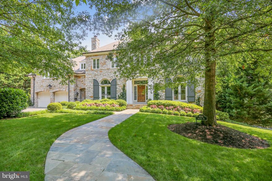 This timeless house, rooted in tradition with a clean and commodious style, is located in desirable Kenwood and overlooks the greenbelt corridor with sweeping park views and accessible interaction with nature. Built on three levels, this stone and stucco home tastefully incorporates superb architectural elements such as a Clive Christian of London Kitchen, pocket doors, custom millwork, distinctive ceiling treatments, arched doorways, and well-proportioned rooms.  The house has excellent flow and an exquisite combination of open and private spaces ideal for every homeowner.
The inviting foyer is between an elegant parlor with charming fireplace and cabinetry, and the formal dining room with stone fireplace and butler’s pantry. The large gourmet kitchen has two sinks, two Miele dishwashers, Sub-Zero refrigerator, set of under counter drawer Sub-Zero refrigerators, wine refrigerator, two Viking wall ovens, a Viking Professional cooktop, a large island and a big walk-in pantry. The breakfast room with extraordinary views, seamlessly transitions into the handsome wood paneled family room with custom built-ins and fireplace with stunning Alexandrita quartzite surround. An exterior side door connects to a convenient mud room and half bath. This floor also features a bright office nook, formal powder room, Lutron RA2 lighting controls, and Sonos. Several sets of double doors lead to a wide elevated rear deck, portions of which are covered, with expansive views that bring nature to the forefront. 
The stylish primary bedroom suite on the upper level has a fireplace bordered by french doors which open to a private balcony, two baths, two walk-in closets, a mini fridge and a versatile sitting room. Three additional well-planned bedrooms, two of which have en suite baths, and a spacious laundry room complete this level.
The walkout lower level is light filled and includes the sizable main area with gas fireplace and plumbing for a kitchenette, if desired. Double doors lead to a flagstone patio with a comfortable table/seating area. Two additional distinct rooms with full baths, a huge lockable storage area with shelving, and a utility room are also featured.
The house exudes an intimate vibe, in spite of the generous square footage, and is enhanced by the beautifully landscaped front yard. Three attached garage spaces, with heaters, and an outside shower add to the property. Designed by award winning GTM Architects and built by acclaimed Sandy Spring builders in 2009.
The sought after Kenwood neighborhood radiates small town charm and boasts numerous cherry tree lined streets that bloom gloriously in the spring. It has easy access to the beloved Capital Crescent Trail and is conveniently located between downtown Bethesda and Friendship Heights, offering multiple grocery stores, trendy shops and dining options.