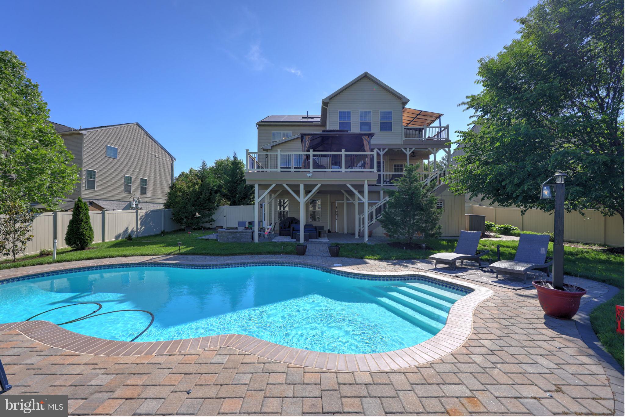 #YouTube property address for virtual video. Ideally situated in the highly desirable and sought-after neighborhood of Woodmore Towne Centre, this home will have everything. It is a rare opportunity to own an absolute gem. This beautiful property will feature the highest end finishes and materials throughout, boasting an approximate living space of 5,087 square feet of living space. Step inside this light-filled open floor plan home and enjoy all its features. This home features an impressive six bedrooms and four full bathrooms. The main level room can be used as an in-law suite. The fully kitted gourmet chef’s kitchen will wow you and all your guests, showcasing the finest appliances and custom-granite countertops. You will find the laundry room, four bedrooms and two full bathrooms upstairs, including the expansive owner’s suite. The additional 300 square feet in the owner’s suite leads to a walkout balcony. On the lower level is a bonus bedroom, gym, wet bar and full bathroom, ideal for guests, nanny/au pair, etc. A full-width upper deck gracefully descends to the lower patio and its focal point — a 50-foot saltwater pool with lighting kit included. This is the largest lot in the community! Come tour this home now to find out more. Additional features include a front-load 2-car garage, outdoor lighting system, irrigation system, outdoor camera system, solar panels, two sheds, fenced in yard, intercom system, HOA clubhouse, basketball court, tennis court, pool community and tot lots. #ClosingWithScales