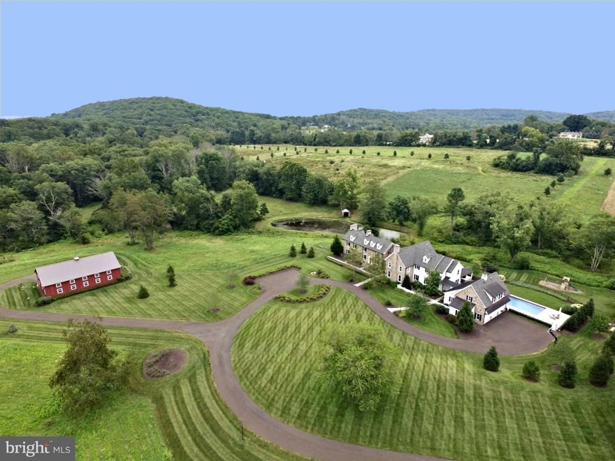 It is the rare occasion that an iconic Bucks County estate with historical significance comes to market. Even more rare is when the original connected side by side stone farmhouse residences - in this instance 1766 and 1770 - are offered completely renovated and with additional new construction added. Such is the case with Plumb Meadow Farm.  With the collective vision and tireless efforts of the sellers, award winning architect Daniel Lloyd, and master builder Richard Zaveta, this splendid 107 acre property presents a once in lifetime opportunity to acquire a legacy Bucks County homestead.  As the last and westernmost portion of an original 505 acre William Penn land grant in 1753,  the property stretched from what is now Covered Bridge Road to the Delaware River. Parts of the original 505 acres are believed to have been used by George Washington's troops as an encampment prior to and after the crossing of the Delaware River for the Christmas Day 1776 Battle of Trenton. Today, the home is nestled just under Bowman's Hill and Bowman's Tower of the adjacent 200 acre Washington Crossing Historic Park, with the famous Van Sant Covered Bridge perched along a portion of the property frontage. Reimagined to perfection in 2015, now offering over 8,800 square feet of finished space, the home features spectacular exposed stone, gleaming oak floors, re-purposed wood and beautiful moldings throughout, all in an idyllic and most private setting. The original 1766 home is now a large formal dining room;  the 1770 structure is now a formal living room w/patio access,  with an exquisite and expansive owners suite now spanning the combined second floors of both.  A gourmet kitchen w/ two islands, breakfast room, walk-in pantry, two story family room with floor to ceiling stone fireplace, office/library and more compliment the first floor. The upper level,  in addition to the owners suite, features three additional bedrooms; one en-suite with two sharing a Jack and Jill bath, and bridge overlook to the family room. The laundry room is conveniently located on the upper level. The lower lever features a finished play room,  with ample storage and additional space to ready finish.  A breezeway leads to the structure housing the three car garage, featuring a large mud room entrance, hobby room, powder room, ample closets and storage, with a spectacular gym above. The home features 5 zones of HVAC, whole house generator, Control 4 security and operating system, Sonos sound system, Lutron lighting, irrigation system and more. The outside of the home is replete with remarkable, immaculate landscaping, two bluestone patios, one of which serves as a large well appointed outdoor kitchen under a large covering, rectangular salt water pool with Turkish travertine surround,  gorgeous spring- fed pond, and 40' x 60'  heated two-story barn / storage building.  The magnificent acreage is a nature lovers dream, featuring approximately 52 acres of forested area with scores of species of both deciduous and non -deciduous  trees, multiple springs, a Blue Heron rookery, roughly 40 meadow acres that can be farmed, over 2,200' of a gently meandering Pidcock Creek, and amazing year-round vistas in all directions. And you can hunt and fish to your hearts content. Finally, the Conservation Easement  governing the property's preservation was amended in 2013, and now features an expanded building envelope allowing for an additional home, outbuildings, equine facilities, nursery and farming operations, etc. All with a lifetime of reduced taxes in perpetuity. Located on the southernmost border of Solebury Township, bordering Upper Makefield Township, the property lies almost equidistant from the beautiful and alluring walking towns of New Hope (12 Minutes) and Newtown (15 Minutes); 60 minutes to Philadelphia, 90 minutes to Manhattan. This is one of the Delaware Valley's most distinguished and investable properties. Now is the chance to make it your very own.