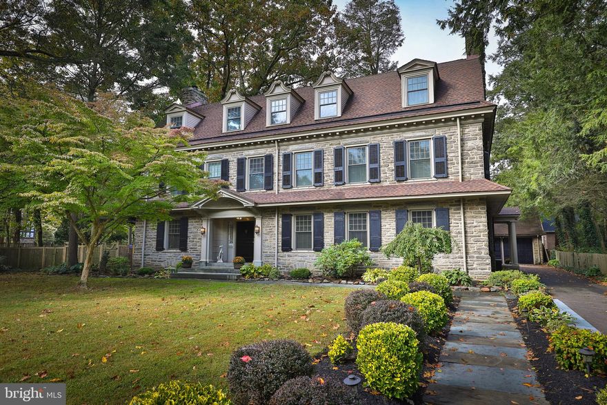 If current events have you seeking a home that can provide a sense of peace and calm,  plentiful outdoor space, and ample room for multiple offices, then look no further.  Designed in 1912 by George T. Pearson, this exquisite stone colonial is throughly updated for today's discerning buyer and exudes warmth and comfort. Upon entering you will be struck by the casual elegance of the detailed woodwork, lovely archways and grand staircase with  arched window on the landing. The living room has a large fireplace flanked by two sets of  French doors leading to the side patio and pergola, a perfect flow for entertaining and for indoor/outdoor living. Host friends and family for dinner in the large dining room, which features a second fireplace, beautiful built-in cabinetry, and a custom-built sideboard. The kitchen has been fully renovated with stunning, leathered granite countertops, Wolfe range,  and large farmhouse sink. The large island provides seating and storage and well as built-in Bosch dishwasher. Exposed brick and stone add a rustic yet contemporary feel, while the butler's pantry with double sink and original tin countertop are a nod to the original design.  A wine cellar sits below the kitchen floor. The kitchen opens to  a bar/sitting area with exposed beams, skylight and renovated half bathroom.  Upstairs you will find the two-room primary suite comprised of a lovely bedroom and a large sitting room, which could easily serve as another bedroom. Stunning primary bathroom features heated floor, beautifully tiled shower with multiple shower heads, double vanity with marble surfaces. From the bathroom or from the hallway you will enter a full custom dressing room complete with built in shelving, a marble-topped island with drawers. Also on this level are an office with plenty of built-in storage,  a laundry room large enough to be nursery or small bedroom, and  another full bathroom. The third floor offers even more flexibility. Two bedrooms and renovated hall bath with clawfoot tub/shower form one wing, perfect for guests. The remaining wing features a third bedroom or office, a smaller unheated room perfect for crafts, yoga or storage,  and a very large bonus space with gorgeous bathroom. This space is currently used a a home gym but would make a lovely primary  bedroom, playroom, etc.  Current owners have made numerous upgrades, including four and half newly renovated bathrooms, each with tasteful tile, marble vanities and high end finishes, fully renovated kitchen and bar, A/C added to 2nd and 3rd floors, 22 new windows, two new plumbing stacks, new boiler in 2018, new hot water heater in 2015, and much more. Situated on just over .5 acres of beautifully landscaped land, you will find plenty of opportunities to spend more time outdoors. Gather with friends and family around the stone fire pit under the newly built pergola, plant vegetables in the raised garden beds, play in the large yard, or relax in one of the many secluded corners. The detached two-car garage has unfinished space above perfect for a studio. The house and grounds are so lovely you may never want to leave but  when you do, you will love being in the heart of popular West Mount Airy.  It is an easy walk to Carpenters Woods, the trails of the Wissahickon, High Point Cafe, Blue Marble Books  and Weavers Way.  This is a truly exceptional property in a coveted location, don't miss your chance to see it!