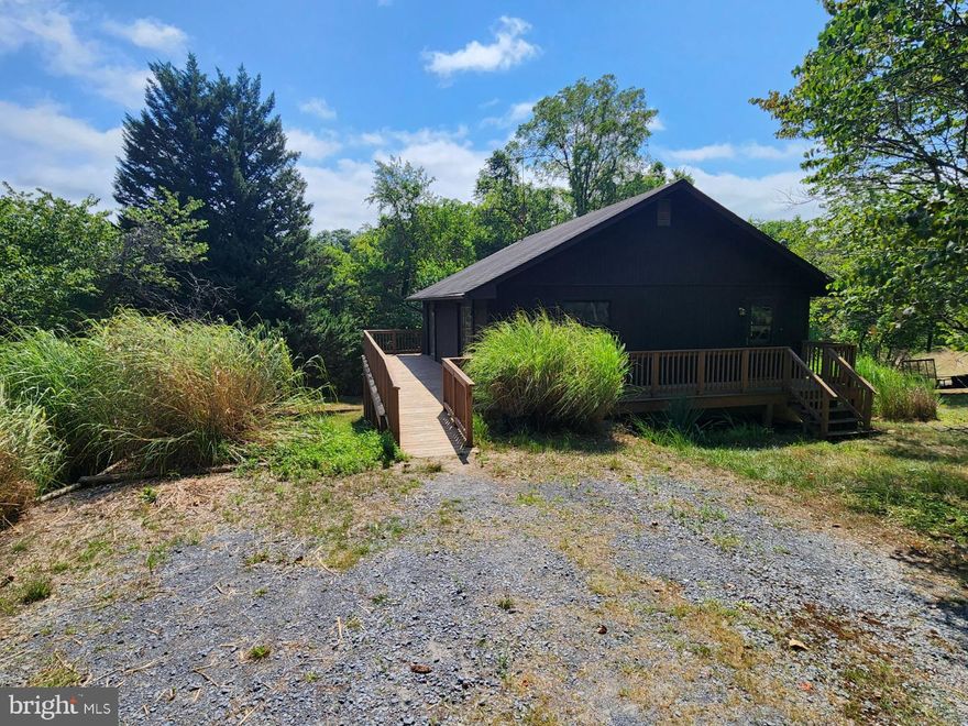 Here is a great opportunity if you have been searching for a weekend getaway, secluded sanctuary or a vacation rental.  This rustic home features 2 bedrooms with 2 full baths and 4 lots that total just over 1.58 acres.  On the main level is a kitchen with table space, living room with 2 Pella sliding glass doors with one that takes you to a 13 x 7 deck that is great for relaxing and enjoying the peace and quiet that Keyes Ferry Acres offers and the other to the side deck that leads to the driveway.  The primary bedroom has brand new carpet, a walk in closet, Pella sliding glass door also leading to the side deck and access to a recently remodeled bathroom that has a large handicap accessible shower stall and built in towel shelves.  On the lower lever,  there is a rec room with access to the backyard and a propane heater, second bedroom, large craft room, 2nd bathroom with tub/shower combo, laundry and utility rooms.  The possibilities are endless with this home due to its location and 3 additional lots.