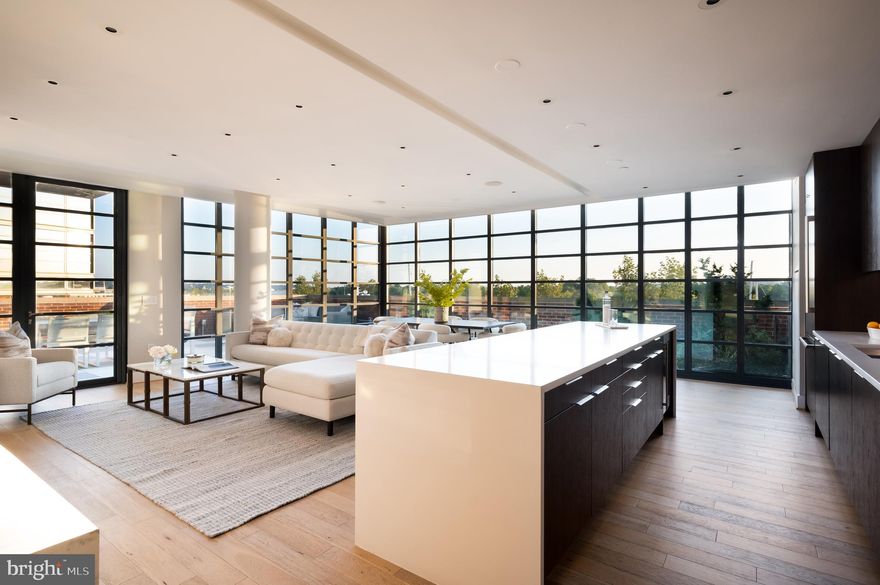 A landmark at the heart of Washington’s iconic Wharf, The VIO is a striking modernist masterpiece conceived by Handel Architects, WDG Architecture, and brought to life by PN Hoffman and Madison Marquette in 2017. With award-winning design and an unbeatable location on the water’s edge, The VIO is the definitive address for waterfront luxury.

At its core lies a truly one-of-a-kind, corner three-bedroom home that seamlessly blends architectural elegance with panoramic views and unparalleled livability. Perched above the shimmering marina, this rare offering provides a front-row seat to the energy and beauty of The Wharf while maintaining a serene, private retreat.

A private elevator entry sets the tone, opening directly into a luminous, open-concept living space. Expanses of floor-to-ceiling, steel-framed windows flood the interiors with natural light and offer unobstructed vistas, while subtly nodding to industrial-modern design. Enhanced by Melissa Colgan Interiors, the home features curated custom finishes and high-end fixtures throughout—each detail thoughtfully considered for both aesthetic and function.

Anchoring the space is a contemporary luxury kitchen, appointed with a full suite of Thermador appliances, rich dark wood cabinetry, dramatic quartz waterfall countertops, and a striking custom backsplash. The adjacent dining and living areas sit beneath a floating ceiling, creating spatial definition and architectural interest. A custom Carrara marble fireplace serves as the focal point of the living area, while a formal powder room nearby features a bold floating marble vanity.

Step outside to the home’s pièce de résistance, a sweeping approximately 800-square-foot wraparound terrace outfitted with a grilling station, fire pit, elegant landscaping, and a 250-foot garden, a verdant escape in the heart of the city. At night, ambient lighting envelops the space in a warm glow, creating an unforgettable atmosphere against the backdrop of the water and city skyline.

The primary suite is its own private sanctuary, introduced by a tranquil sitting area. Beyond a custom dressing area lies the spa-inspired marble-clad bath, complete with dual vanities, soaking tub, and glass-enclosed shower. Two additional bedrooms include a flexible study with built-ins and upgraded closets and share a stylishly appointed hall bath with dramatic dark tilework. A large in-unit laundry room with side-by-side washer and dryer adds practicality to luxury.

Smart home features include Lutron lighting controls and motorized shades throughout. Two underground parking spaces convey, an exceptional amenity in the urban core.

For those seeking even more flexibility, an exclusive à la carte opportunity exists to acquire the adjacent Residence. This studio unit features a sleek galley kitchen, full bath, in-unit laundry, and additional storage, ideal for a guest, au pair, or extended-stay family member. The open layout enjoys the same striking views and finishes for seamless integration.

The VIO offers full-service living defined by sophistication and ease. Amenities include 24-hour concierge, porter service, a private porte-cochère, fitness center, yoga studio, resident lounge with espresso bar, and a saltwater infinity pool and sun deck overlooking the waterfront.

Just outside the lobby, discover The Wharf’s vibrant cultural scene, trendy restaurants, boutique shopping, live music venues, and year-round events, all within steps, with easy access to the rest of D.C. Blending refined architecture, breathtaking views, and the most coveted location in the city, this Residence at The VIO is a singular opportunity for the discerning buyer. More than a residence, this is a front-row seat to life on Washington’s waterfront, bold, beautiful, and entirely without equal.