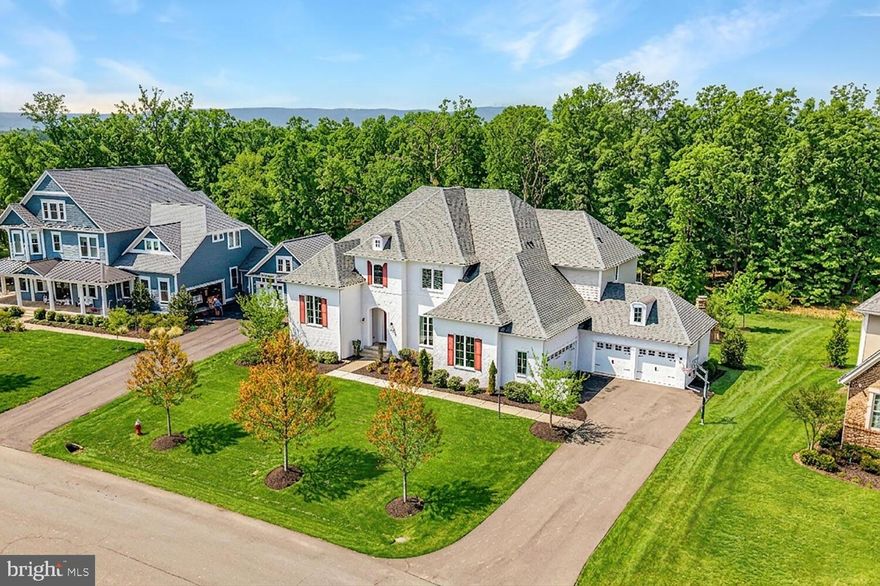 Quite simply, one of the finest homes in all of Willowsford. A rarely available Great Falls model by Drees Homes, this exceptional residence offers one of the largest floor plans in the community—boasting over 7,000 finished square feet and a commanding presence from the moment you arrive. Perfectly sited on a ½-acre lot backing to trees and protected conservancy land, the home showcases incredible curb appeal with its striking white brick façade, refined architectural detailing, and a welcoming covered front entry.
<br><br>
Inside, a dramatic two-story foyer makes an unforgettable first impression, framed by a wide, elegantly appointed staircase, detailed moldings, and expansive windows that flood the space with natural light. Designer finishes and hand-scraped hardwood floors flow throughout, creating a seamless blend of sophistication and warmth. Formal living and dining rooms offer timeless spaces for entertaining, with the dining room beautifully anchored by a statement chandelier. Just off the staircase, a private home office provides a quiet and refined work-from-home retreat.
<br><br>
The main living area is anchored by a stunning family room featuring a coffered ceiling, stone-surround gas fireplace, and custom built-ins—an inviting yet elevated space for everyday living. The gourmet kitchen is a true showpiece, thoughtfully designed with dual islands, high-end appliances, abundant cabinetry, and effortless flow into the sunlit breakfast room, highlighted by a designer light fixture. A butler’s pantry with wine storage enhances entertaining, while the expansive prep kitchen—complete with its own island and second washer/dryer hookup—offers unmatched functionality and organization.
<br><br>
A main-level guest suite with a full bath provides exceptional flexibility for multigenerational living or extended stays. Upstairs, the luxurious primary suite is a private retreat, featuring a spacious sitting room and a spa-inspired bath with a freestanding soaking tub, a walk-through shower with dual shower heads, and separate vanities. Each additional upper-level bedroom is thoughtfully designed with its own en-suite bath and walk-in closet, while a conveniently located upper-level laundry room adds ease to daily living.
<br><br>
The fully finished walk-up lower level continues to impress, offering a generous rec room, the 6th bedroom and full bath, and a versatile den ideal for a home theater, fitness studio, or hobby space. Outdoor living is equally exceptional, featuring a covered porch with ceiling-mounted heaters, a paver patio, and a fire pit, all set against a backdrop of peaceful wooded views—perfect for year-round enjoyment.
<br><br>
Completing the home is a four-car garage—an exceptional feature that perfectly complements the home’s impressive scale and everyday functionality. 
<br><br>
Willowsford is Northern Virginia’s premier community, offering a one-of-a-kind lifestyle rooted in scenic beauty, sustainability, and farm-to-table living. Spanning 4,000 acres, this thoughtfully designed community features four distinct villages surrounded by preserved open spaces, lush forests, rolling meadows, and sustainable farmland maintained by the Willowsford Conservancy. Residents enjoy world-class amenities, including Sycamore House and The Lodge at Willow Lake, with resort-style pools, fitness centers, and farm-inspired culinary programs. An extensive trail network, a fishing lake, an amphitheater, a dog park, and nature-inspired recreational spaces further enhance the vibrant outdoor lifestyle. 
<br><br>
Conveniently located near major commuter routes, the Dulles Greenway, and the Metro Silver Line, Willowsford provides easy access to shopping, dining, and business hubs. It is also served by Loudoun County’s highly sought-after school system, making it an exceptional place to call home.