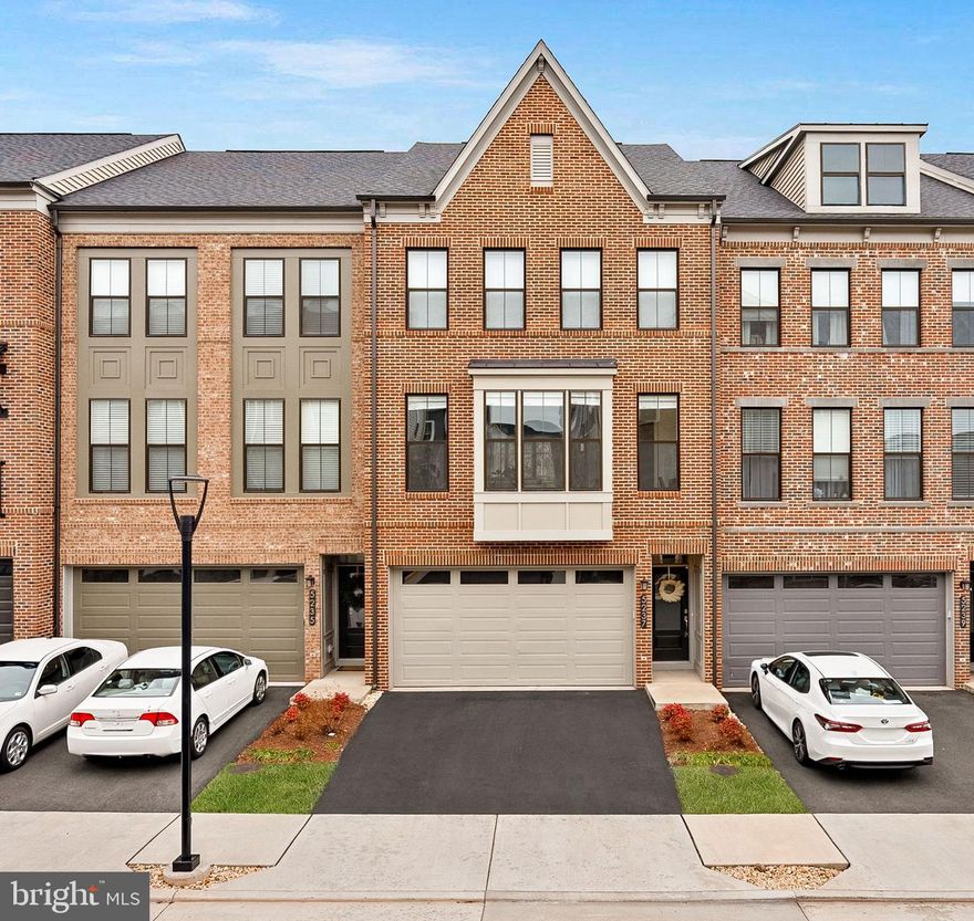 Welcome to 5237 Ridgeview Retreat, a beautifully upgraded Miller & Smith Clarion model, built in 2023 and located in the highly desirable Retreats at Westfields. This luxury 4-level, front-load 2-car garage townhome offers an exceptional blend of modern design, thoughtful upgrades, and flexible living spaces.
Offering 2,774 square feet, 4 bedrooms, and 3.5 bathrooms, the home is filled with natural light and enhanced by 9-foot ceilings throughout, a newly added coffered ceiling, and custom carpentry details throughout the home. The entry level includes a private bedroom and full bath—ideal for guests or a home office—along with a spacious recreation room that opens to an oversized patio, backing to mature trees for rare privacy. The main living level is designed for both entertaining and everyday living, showcasing a chef-inspired kitchen with an oversized center island, 42” white shaker cabinetry, quartz countertops, Samsung stainless steel appliances, enhanced luxury vinyl plank flooring, and a generous kitchen pantry.  The home also includes custom motorized window treatments (over a $6k investment), conveniently controlled from your remote.  The expansive great room is elevated by the custom coffered ceiling and built-in carpentry, and flows seamlessly to a 10’ x 17’ Trex deck with black aluminum railing, offering peaceful tree-lined views. A dedicated dining area and a large powder room complete this level. Upstairs, the primary suite provides a true retreat, featuring a spa-like owner’s bath with dual comfort-height quartz vanity and a large walk-in shower. Two additional bedrooms, a full bath, and a conveniently located laundry area complete the bedroom level. The top-level loft offers nearly 500 square feet of light-filled flex space, ideal for a home office, gym, media room, or additional living area, and features its own dedicated HVAC zone. With premium builder selections, a newly added coffered ceiling, custom carpentry throughout, designer lighting, upgraded flooring, and refined finishes, this home delivers luxury living in a tranquil setting. Ideally located with easy access to shopping, dining, and major commuter routes—this is truly a commuter’s dream.