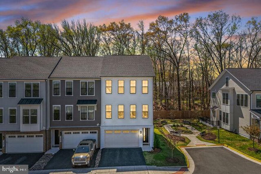 Better than new, this stunning end-unit luxury townhome showcases over $100K in premium upgrades and a sophisticated four-level modern design filled with natural light and upscale finishes throughout. This home offers exceptional energy efficiency with dual-zoned HVAC systems, a Rinnai tankless water heater, R-38 attic insulation, and durable brick & Hardie Plank siding. Elegant 7” engineered hardwood flooring extends throughout the home, enhancing its seamless, contemporary feel. The main level features 10-foot ceilings and an impressive open-concept gourmet kitchen designed for both everyday living and entertaining, complete with quartz countertops, waterfall island, pendant lighting, upgraded GE stainless steel appliances, custom soft-close cabinetry, designer backsplash, and range hood. The adjacent living area opens to an oversized Trex deck overlooking peaceful wooded views—perfect for relaxing or hosting guests. Upstairs, the luxurious primary suite offers a spa-inspired bath with walk-in shower, double vanity, and designer tile finishes, along with the convenience of a bedroom-level laundry room. The top-level loft and rooftop terrace provide the ultimate indoor-outdoor lifestyle, ideal for entertaining or enjoying sunset views. This level also features a private office with bath and wet bar, enhanced by large windows with expansive views—perfect for working from home or hosting guests. The lower level includes walk-out access to the backyard and direct entry to the garage, adding flexibility and convenience. Ideally located near top shopping, dining, and entertainment, with easy access to Route 28, Route 50, I-66, and Dulles International Airport, this home offers the perfect combination of luxury, location, and lifestyle. A rare opportunity to own a model-like end-unit townhome with rooftop terrace and premium upgrades—don’t miss it!