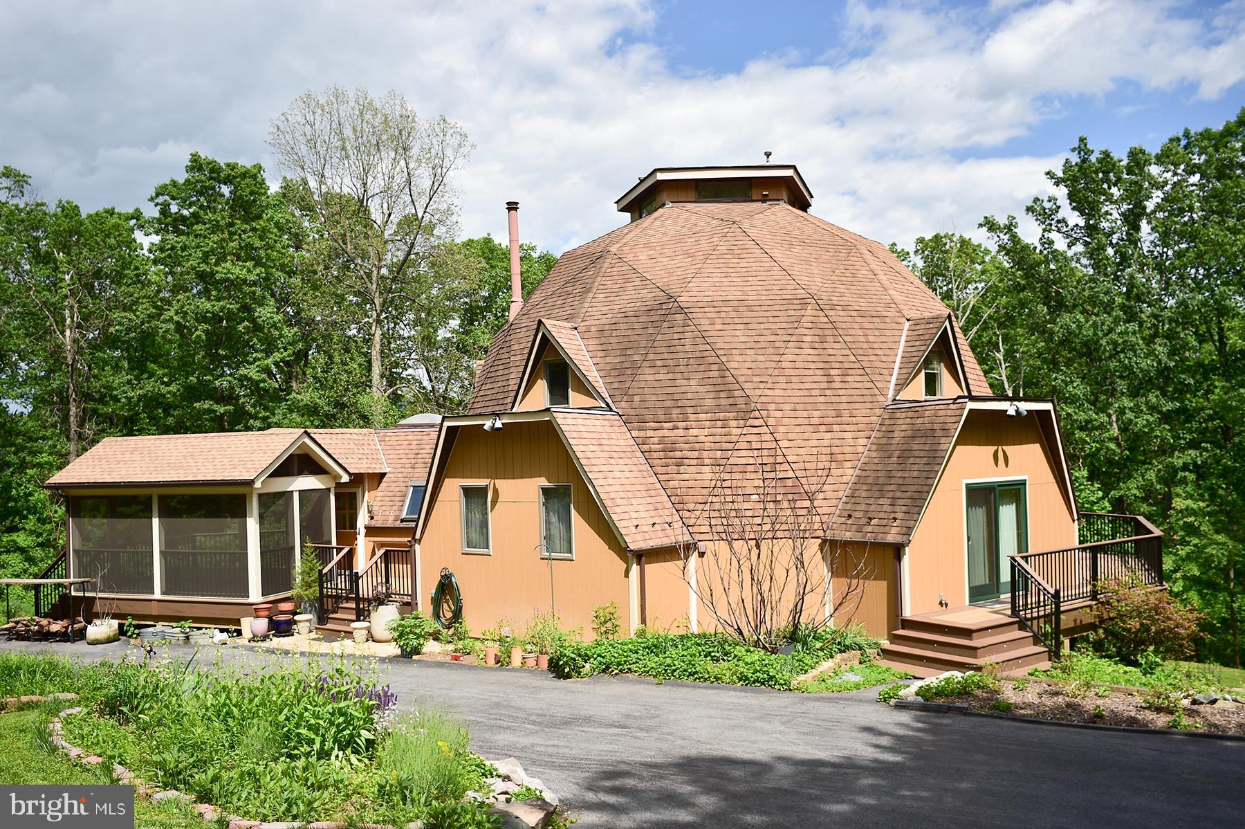Rare Opportunity! Discover this stunning custom-built geodesic home set on 8 private, wooded acres along scenic Trego Mountain Road. This one-of-a-kind property includes two parcels: a 3-acre homesite and a separately deeded, buildable 5-acre lot with existing plat, a gentle stream meanders through this additional lot — perfect for future development or preserving your privacy. Offering over 4,800 sq ft of living space, this architecturally unique home features 4 bedrooms and 4 full bathrooms with a versatile open floor plan bathed in natural light from an abundance of windows and skylights. The heart of the home is the gourmet kitchen, renovated in 2019, featuring professional-grade Thermador appliances, granite countertops, a double sink, a large garden window, and custom built-ins. The kitchen flows into a dramatic three-story great room centered around a Vermont Castings woodstove and topped with a striking dome skylight. The main level also includes a formal dining room that opens to the wraparound composite deck, plus two bedrooms and two full bathrooms. Upstairs, the primary suite offers a spacious private bath and access to a loft area. The third floor includes an open loft, perfect for a reading nook, office, or creative space. The fully finished walkout basement adds incredible flexibility, with a spacious family room, two bonus rooms, a full bath, free standing propane stove and a utility room — ideal for an in-law suite, guest quarters, or hobby space. Enjoy the peaceful surroundings and extensively landscaped gardens, including raised vegetable beds, herb and perennial gardens, fruit trees, a native plant garden, blueberries, and asparagus beds. Additional features include a detached oversized 2-car garage, ample driveway parking, and easy access to RT 340, I-70, Alt-40, Frederick, and Washington, D.C. Don’t miss your chance to own this truly unique mountain retreat — schedule your private tour today!