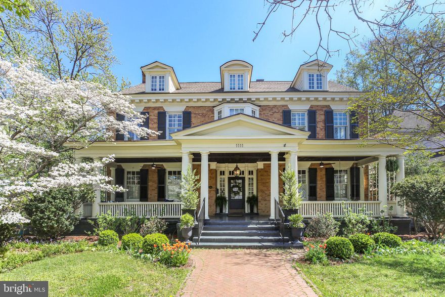 Are you looking for a distinguished downtown Fredericksburg residence that blends architectural elegance with modern luxury and unforgettable entertaining spaces? Positioned on a coveted corner lot within the Historic District, this exceptional 5-bedroom, 4 full and 3 half bath residence offers 5,239 square feet of refined interiors, bespoke craftsmanship, and a fully realized indoor-outdoor lifestyle—complete with a two-car driveway providing valuable off-street parking just steps from the city’s finest dining, shops, and riverfront. A gracious covered front porch with a richly detailed wood-paneled ceiling sets an impressive introduction, leading to a striking entry framed by transom windows and sidelights. Inside, the foyer reveals a sweeping curved staircase and integrated built-in coat closets, establishing architectural sophistication from the moment of arrival. The main level is defined by rich hardwood flooring, plantation shutters, oversized windows, and refined millwork. The formal dining room with chair rail and crown molding flows seamlessly into the gourmet kitchen, designed for both intimate gatherings and grand entertaining. An expansive island anchors the space, complemented by floor-to-ceiling custom cabinetry with soft-close drawers, display shelving, pull-out appliance storage, farmhouse sink, and a custom range hood highlighting the Wolf appliance suite with six-burner gas range, built-in oven, and microwave. A well-appointed butler’s pantry and discreet half bath enhance functionality, while a private office with built-ins and patio access adds versatility. The kitchen opens to a gracious family room with statement fireplace and custom shelving, while a formal living room with gas fireplace provides an additional refined gathering space. French doors reveal a sophisticated bar room featuring cork flooring, custom cabinetry, sink, ice maker, wine storage, arched windows, and backyard access—designed for elevated entertaining. Upstairs, the primary suite is introduced through glass French doors and includes a sitting room with bay window seating and storage, custom built-ins, and hardwood flooring. The spa-inspired bath offers dual vanities, walk-in shower with seating, separate water closet, and a custom walk-in closet with integrated laundry. Three additional bedrooms provide generous storage and architectural detail, complemented by a beautifully appointed hall bath. The third level presents a finished attic retreat with exposed beams, mini-split system, full bath, and flexible living space ideal for guests, studio, or private quarters. The partially finished lower level extends the home’s versatility with exposed brick, wet bar with wine refrigerator, half bath, exterior access, and a flexible guest or fitness suite complete with Murphy bed and full bath featuring a steam shower. Ample unfinished storage and expanded laundry capacity provide added convenience. The fenced rear grounds offer a brick patio and manicured turf framed by mature landscaping for privacy. The detached two-car garage has been transformed into an extraordinary all-season pavilion with fireplace, Wolf grill, quartzite countertops, Sub-Zero refrigeration, bar seating, hot tub, and half bath—an amenity rarely found within the Historic District. Don’t miss the opportunity to own one of downtown Fredericksburg’s most comprehensively appointed residences.