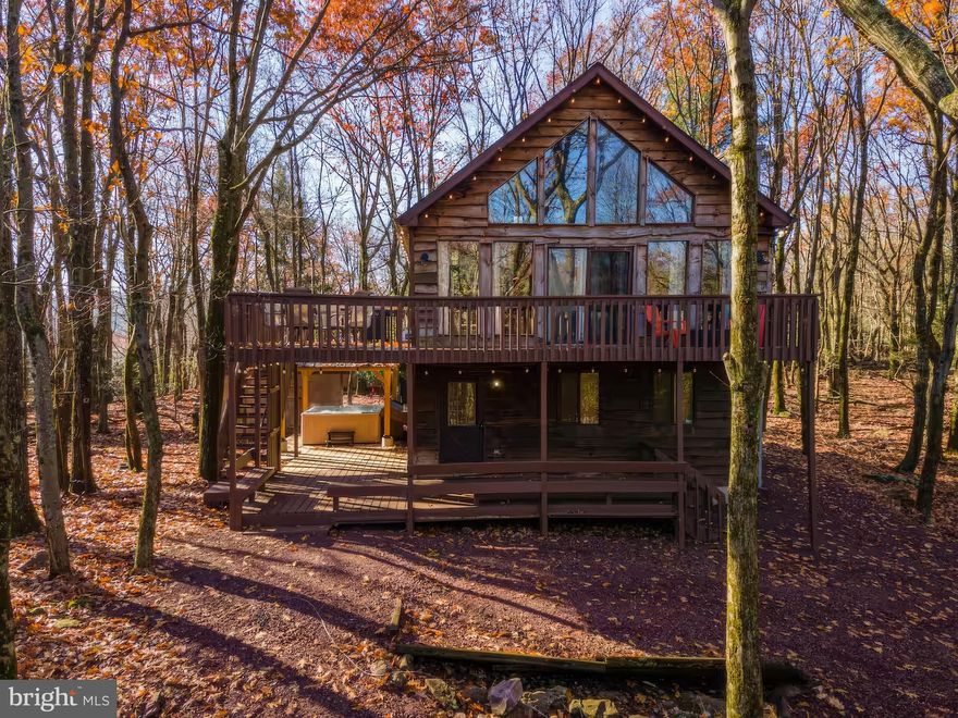 Discover the perfect blend of rustic charm and modern convenience in this stunning chalet-style home, nestled in the highly desirable Lake Harmony Estates. This area is a haven for second-home buyers and investors alike, thanks to its allowance of short-term rentals—offering you the incredible opportunity to offset ownership costs with rental income. This fully renovated, three-story retreat exudes character and warmth, surrounded by a phenomenal tree-lined lot that ensures privacy and tranquility—everything a second-home owner or renter could dream of. Step onto the welcoming rustic entrance, where ample parking, two expansive decks, and a brand-new covered hot tub set the stage for relaxation and enjoyment. Just a short walk away, you'll find the community’s private beach, local restaurants, and a charming ice cream shop, making this location as convenient as it is picturesque. Inside, the home spans three floors of beautifully updated living space, perfect for spreading out and entertaining. The open-concept kitchen and living area is a showstopper, featuring newer cabinets, a stylish tile backsplash, stainless steel appliances, and a large peninsula island—all complemented by cozy wood-tone laminate vinyl plank flooring and oversized windows that flood the space with natural light. With 4 spacious bedrooms adorned with wood trim and inviting furnishings, 2 fully renovated bathrooms boasting new vanities and sleek tile showers, a versatile tea room, and a game room, this chalet offers flexibility and comfort for all. The game room, with its wood-clad walls and ceilings, doubles as a second living space, adding even more appeal. Outfitted with economical ductless heating and cooling, this home combines modern efficiency with timeless appeal. Whether you're seeking a lucrative rental property or a private getaway near Lake Harmony’s best amenities, this chalet delivers the ultimate in style, space, and opportunity. Don’t miss your chance to own a slice of paradise.