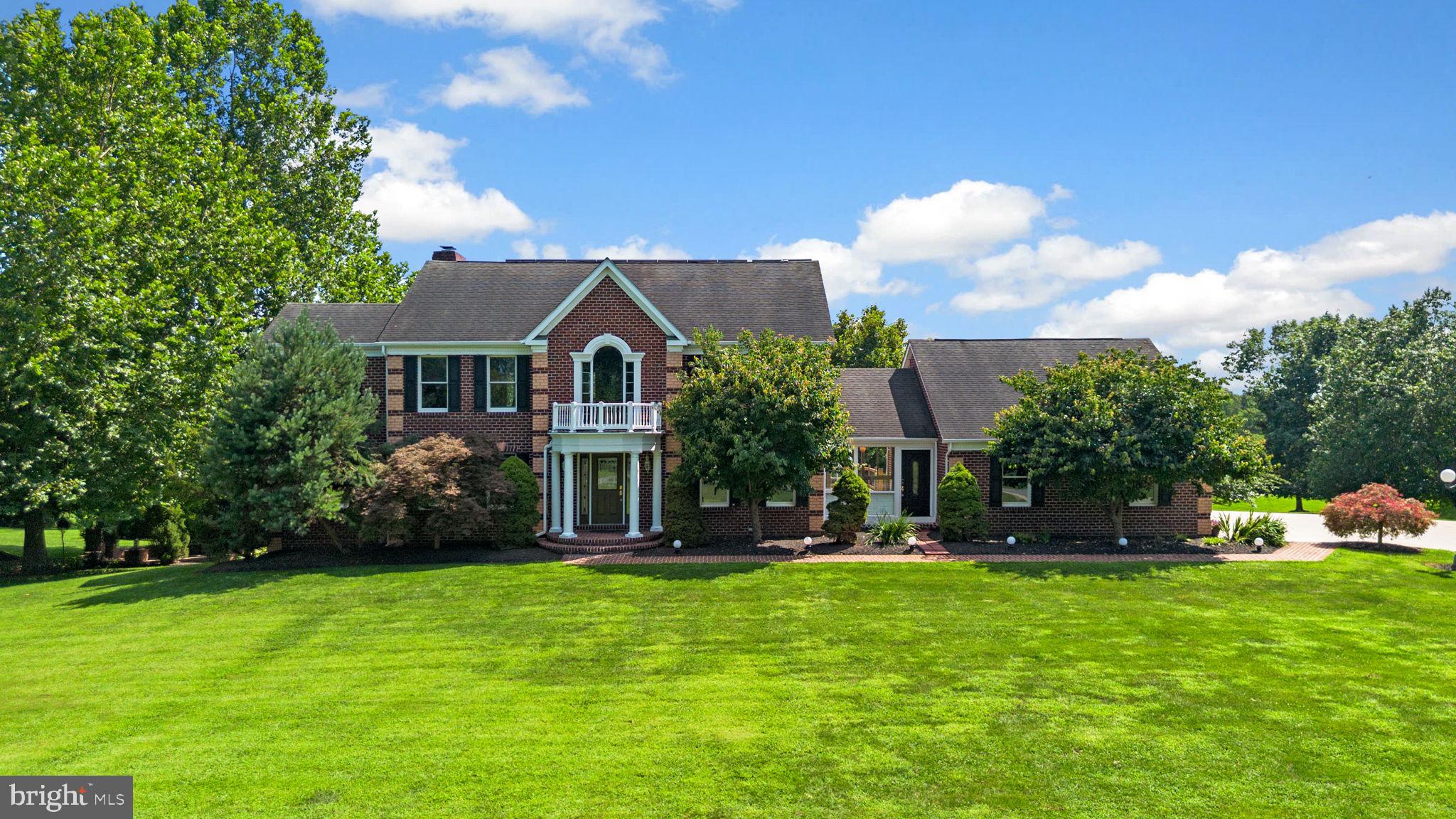Gracefully set on over three scenic acres, this prestigious Colonial offers a perfect blend of timeless elegance, modern comfort, and serene privacy. The home impresses from the start with gorgeous curb appeal—featuring a mostly brick exterior, a grand entryway with a Juliette balcony and stately columns, professional landscaping, a sweeping front lawn, and a long private driveway.
Inside, the thoughtfully designed floor plan is bathed in natural light and enhanced by rich hardwood flooring throughout most of the main and upper levels. A dramatic two-story foyer welcomes you in and opens to a formal living room with French doors, elegant chair railing, and hardwood floors. Opposite the foyer, the formal dining room provides a sophisticated setting for gatherings, complete with classic wainscoting details. Another set of French doors leads to a private study or home office, beautifully appointed with built-in bookcases. Nearby, a powder room, laundry room, and butler’s pantry add everyday convenience, while a charming brick breezeway—with front, back, and garage access, along with a split air system—offers flexibility as an additional indoor-outdoor living space, adding both warmth and character to the home’s layout. The spacious family room offers a cozy retreat, featuring hardwood floors, a brick-accented gas fireplace, a bay window, and access to the rear deck. The adjoining eat-in kitchen serves as the heart of the home, showcasing granite countertops, a central island with bar seating, a built-in writing station, warm-toned backsplash, and sleek black appliances. Just off the kitchen, a sun-filled breakfast room with soaring vaulted ceilings, a statement chandelier, and panoramic views of the backyard creates the perfect space for casual dining.
Upstairs, discover four generously sized bedrooms, each with hardwood floors, and two full bathrooms. The luxurious primary suite is a serene escape, complete with high vaulted ceilings, double closets, a cozy sitting area, and a beautifully updated spa-like ensuite bath featuring an oversized dual-sink vanity and a wet-room style glass-enclosed shower with a Roman soaking tub inside. The fully finished walk-out lower level offers incredible flexibility and space. Highlights include a large recreation room with a fireplace, a guest room with plush carpeting, multiple versatile bonus rooms—ideal for a home gym, office, or media space—a partitioned craft or playroom, a finished storage area, and a full bathroom.
Outdoor amenities are just as impressive, including a deck, a covered patio, curated landscaping, a refreshed private pickleball court, a dedicated firepit courtyard area, and a large fully-fenced open yard perfect for entertaining, complete with a storage shed and garden area.