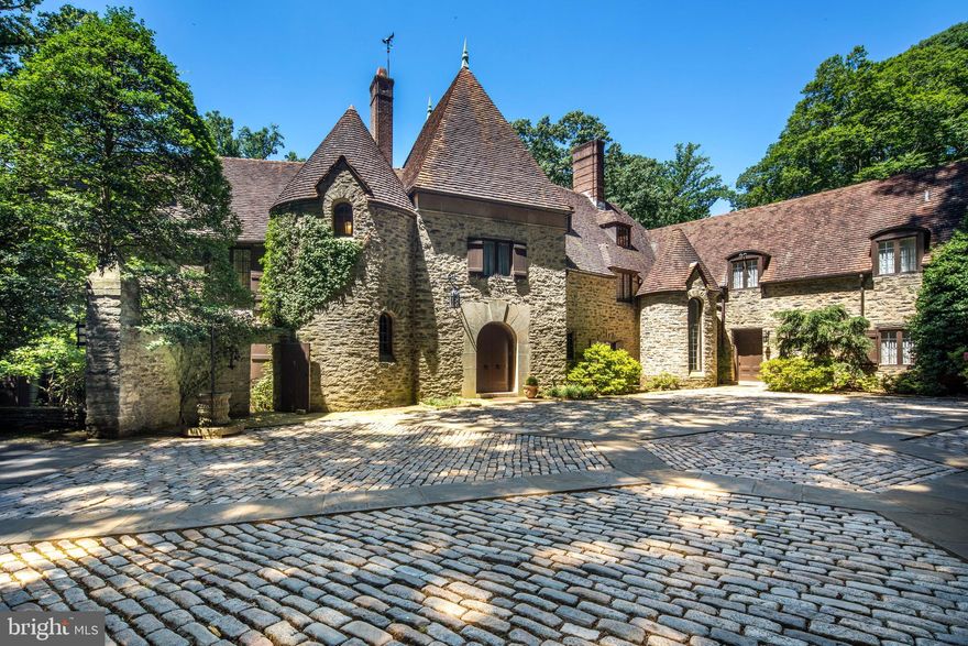 Follow a winding drive to an impressive high walled granite-block arrival court. Two stone turrets mark the formal and family entrances while a porte-cochere leads to the rear courtyard, garages and independent guest or staff quarters. Using the natural topography of the land, the home is built into the hillside, creating sweeping vistas while a ribbon of blue stones terraces provides for picturesque entertaining with views of the gardens and homes 12+ acres. A hidden treasure with much of the original elements including flooring, mill and iron work still intact. The floor plan of the house is also informed by the flow of the grounds with most rooms having a front to back opportunity to take in the sprawling landscape . Enter to a large front to back reception foyer . To the left is a step-down Living Room with centrally positioned wood burning fireplace and multiple sets of French doors on either side. Ideal for an intimate outdoor gathering, find a secluded terrace off this formal space. A gallery hall connects the entry area to both a handsome fireside family room and a large and elegant dining room also with fireplace. A swinging service door opens to the kitchen, large Butlers pantry, home office and generous walk-in storage. Enclosed at some point in the 1970s, the pool offers expanded family space/recreational space with a large solarium adjacent to the pool and his and her indoor cabana areas with baths. Finding our way back to the main entry a soaring stair tower leads to the second floor and an exceptional, expanded Primary suite. In addition to the sleeping chamber the suite offers his and her baths, ample closets and a second level family room with fireplace or handsome dressing room. As many as 6 additional bedrooms and 3 additional full baths are found on this level and can be paired as suites or office spaces. The third level also has a large bedroom, full bath, and walk-in closet.