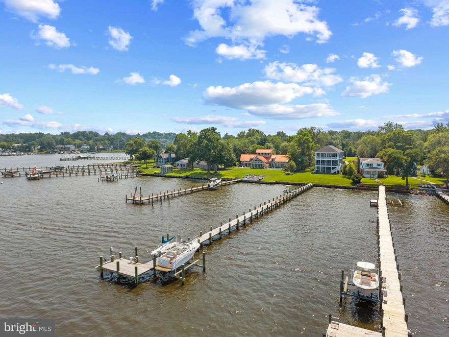 Built in 2021 and lightly lived-in, this coastal waterfront home is perched on the shores of the Magothy River and Chesapeake Bay offering endless water views. Spanning three levels and designed to embrace the beauty of its setting, this residence offers elegant interiors, seamless indoor-outdoor living, and sweeping water views. The entry level features a bonus room/bedroom with full bath, ideal for guests or flexible living space. The sliding glass doors open onto the covered patio complete with a swim spa - perfect for unwinding after a day on the water. The gently sloping lawn leads down to the water's edge and private pier.  A 300-foot private pier with water, electric, boat lift, and two jet ski lifts invites endless enjoyment on the river. Live the waterfront lifestyle with ease! Back inside, the main level unfolds with an open floor plan designed for both quiet moments and lively gatherings. Walls of windows and doors frame sweeping water views and open to a full-width screened porch—an ideal space for morning coffee, alfresco dinners, or simply watching sailboats drift by. The wood-burning fireplace and stunning coffered ceiling anchor the living room and dining area while the gourmet kitchen—with its oversized island, butler’s pantry, and generous workspace—is a natural gathering place. An office/bedroom with full bath adds function and flexibility. The upper level is a private retreat, where the primary suite captures the essence of waterfront living. Wake to the sunrise over the Bay from your private balcony, unwind by the gas fireplace, and rejuvenate in the spa-like bath featuring a freestanding bubbler tub, glass-enclosed shower, dual sinks, and a custom walk-in closet. Two additional bedrooms with shared bath offer plenty of room for family and friends. The oversized 3.5-car garage includes workshop space and generous storage. An elevator shaft serves all three levels, ready for future installation.  The Shore Acres community beach, picnic area, boat ramp and clubhouse are within walking distance and the property is located in the highly coveted Broadneck school district. It’s the perfect location to quickly access downtown Annapolis for shopping and dining or jump on Rt. 50 to get back to Washington, DC. Thoughtfully designed for both daily comfort and unforgettable coastal living, this home is a rare opportunity to embrace life on the water in timeless style. Welcome Home!