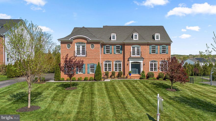Spanning over 7,400 square feet across three beautifully finished levels, this exceptional residence showcases a luxurious interior defined by refined architectural detail, elegant finishes, and thoughtfully designed living spaces. // Rich hardwood floors extend throughout the main level, beginning in a grand two-story foyer adorned with a sweeping curved staircase, intricate stacked moldings, and classic wainscoting. French doors open to a private office featuring a statement chandelier and graceful curved transom windows. To the right, the open-concept formal living and dining areas are artfully defined by architectural columns, highlighted by stacked moldings, arched transom windows, and detailed millwork, creating a sophisticated setting for both everyday living and entertaining. // At the heart of the home, the stunning designer gourmet kitchen is a true showpiece, blending style and function with premium finishes throughout. Highlights include granite countertops, white shaker cabinetry, a striking herringbone Carrara subway tile backsplash, stainless steel appliances, and an espresso-toned oversized island with bar seating, pendant lighting, and built-in wine storage—beautifully contrasting the lighter cabinetry. A built-in workstation and writing desk add versatility, while the adjacent breakfast room offers a cozy setting with direct access to the covered porch. // The expansive family room just beyond is framed by elegant columns and enhanced by transom windows, custom blinds, and continued stacked moldings, and flows seamlessly into a well-appointed mudroom and powder room. // The upper level features four generously sized bedrooms, each with access to a full bathroom and a walk-in closet, along with a conveniently located central laundry room. The luxurious owner’s suite serves as a private retreat, complete with a vaulted sitting room and a double-sided gas fireplace, dual walk-in closets including one outfitted with a California Closets® organization system, and a spa-inspired bath featuring dual oversized granite-topped vanities, a dedicated makeup station, an oversized frameless glass shower, a Kohler® soaking tub, and exquisite herringbone tile flooring complemented by Carrara subway tile throughout. // The fully finished lower level expands the living space with a large open recreation room centered around an additional stone-accented gas fireplace, a stylish wet bar with breakfast seating and pendant lighting, and walk-out access to the backyard. This level also includes a fifth bedroom with an attached full bath, ideal for guests or extended living arrangements. // Outdoor living is equally impressive, highlighted by a covered deck with a full stone fireplace and a built-in television space. The backyard is a private oasis, featuring an in-ground heated saltwater pool with a waterfall feature, an expansive patio, lush landscaping, and a fully fenced yard backing to mature trees for added privacy. Owned solar panels enhance the home’s efficiency and provide long-term energy savings. // Situated within the prestigious Walnut Creek community and zoned for Howard County’s highly rated River Hill School System, this home offers the added convenience of all three school bus stops located right at its doorstep. Ideally positioned near major commuter routes, as well as a variety of shopping, dining, and everyday conveniences, offering the perfect balance of luxury and accessibility.