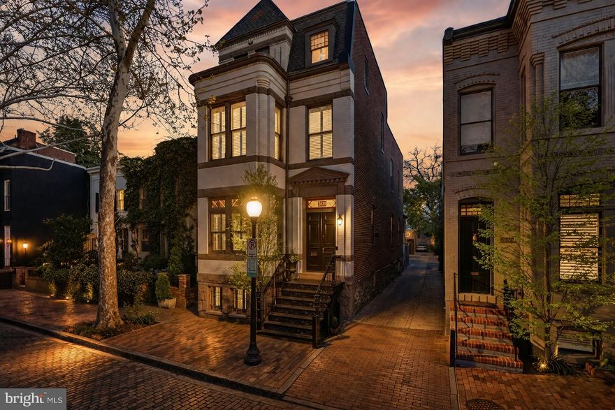 Set along this storied block of P Street—one of only two West Village streets, along with O Street, where original trolley rails still run through the old brick roadway—this historic, standalone residence is a rare find. Built in 1885, and recently renovated throughout, the Victorian home combines timeless architectural character with sophisticated modern upgrades across approximately 3,855 square feet of refined interior living. The property boasts 5 bed, 5.5 bath and garage parking, plus exceptional privacy and outdoor space. An extensive renovation completed in 2019 elevated both functionality and design throughout the home. The expanded gourmet kitchen features top-of-the-line appliances, custom cabinetry, and premium finishes. Southern-facing windows are outfitted with app-controlled The Shade Store motorized blinds, offering seamless light and privacy control. Glass flooring offers ample light to the lower level office. The renovation added a full bath on the second level, enhancing livability, while the lower level offers a sun-filled office or flex space with radiant heated floors, along with additional storage and a new laundry room. Throughout the home, solid plantation shutters, hardwood floors, and preserved historic details reflect classic Georgetown craftsmanship. Modern infrastructure upgrades include a leak defense monitoring system designed to protect against water system issues, providing peace of mind. Outdoor living is complemented by a charming rear patio with new stonework and custom water feature. The detached parking is a rare feature in this premier location. Just moments from Georgetown’s celebrated shops, dining, waterfront, and parks, this exceptional West Village offering delivers historic elegance, modern comfort, and uncommon privacy in one of Washington’s most prestigious neighborhoods.