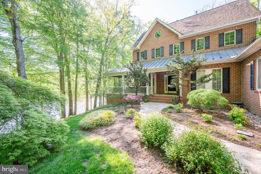Enjoy over 700 feet of Occoquan River water frontage, directly across from the protected lands of Fountainhead Regional Park. This custom all-brick home sits on 5+ private wooded acres, just south of Bull Run Marina.  The original owner surveyed and designed this home to be above the 100-year flood zone and to offer water views from nearly every room.  A landscaped entrance welcomes you with spectacular panoramic water views and a travertine stone walkway, elegant brick steps, and a covered entryway accented by a copper roof feature that wraps around the covered corner screened-in-porch. Inside, enjoy 10-foot ceilings, solid oak floors, and a newly renovated gourmet kitchen with high-end appliances, custom cabinetry, and quartz countertops, while a striking granite island offers additional seating. The great room impresses with a floor-to-ceiling stone fireplace, while expansive glass door sliders lead to a raised terrace and the screened-in-porch—perfect for peaceful, stunning river views. The upper level boasts four spacious bedrooms, each with ensuite baths and walk-in closets. The luxurious owner’s suite features a stone fireplace, dual custom closets, and a spa-style bath. The finished walkout lower level is built for entertaining, with a striking stone bar, guest suite, and access to a patio overlooking the water.  A private dock offers direct river access for boating and fishing, while the finished garage and separate temp-controlled workshop provide added convenience. Located minutes from Clifton’s charming shops and dining—this rare riverfront retreat has it all.