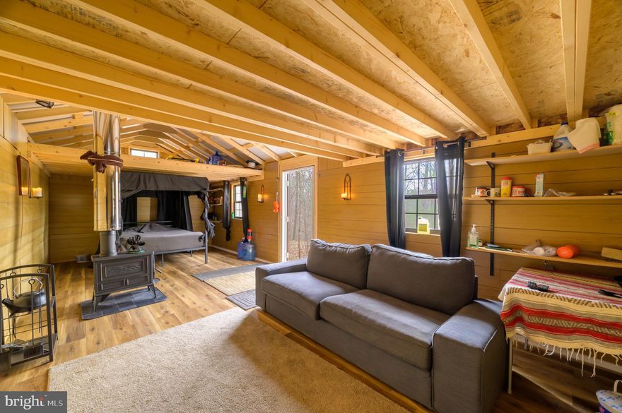 Are you looking for the perfect weekend getaway, hunting property, or lot to build your forever home? Nestled in the woods of Back Creek Valley in southern Berkeley County, WV, is this unique property of five unrestricted acres. There is a 12x28 building that has been converted into an off-grid living space. This could have great potential as an Airbnb glamping cabin. There is a Vermont Castings wood-burning stove to keep you warm on those chilly nights. The current owner utilized a solar generator to power the TV for entertainment. Just imagine being cozied up on the couch, watching a movie with a fire going, while listening to the rain fall on the metal roof! The walls are insulated, and the floors have been double-insulated. Gutters have been installed, which tie into a rain collection barrel. All furnishings can be conveyed with an acceptable offer. This cabin is entirely off-grid; there is no electricity, well, or septic system currently installed. There is an outhouse that can accommodate a compost toilet if desired. The property has previously been perk-approved for a three-bedroom septic system, and an area has already been dug for a foundation. There is a small creek that meanders along the lower end of the property. Wildlife sightings here are frequent, including squirrels, turkeys, deer, and the occasional bear. Sleepy Creek Wildlife Management Area is nearby, comprised of nearly 23,000 acres of public land for hiking, hunting, mountain biking, and featuring a 205-acre lake for fishing and boating. Schedule your private showing today to see what this amazing property has to offer!