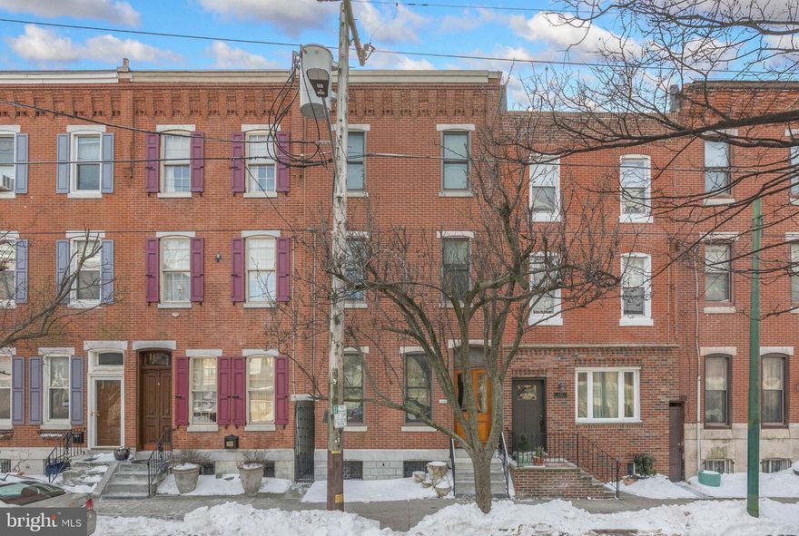 Overflowing with original character, abundant space, and natural light, 230 Morris St seamlessly blends century-old charm with modern living in the heart of Pennsport. This 2,500+/- sqft 3-story home offers 5 bedrooms, 1 bathroom, a custom chef's kitchen, a secluded garden patio, and a huge basement. The exterior makes an impressive first impression with its towering brick facade and elevated entry, highlighted by stunning wood double doors. Just inside, a vestibule provides a welcoming buffer from the outside world, ideal for coats and shoes. The large, open, and airy living room is framed by soaring ceilings and tall windows that flood the space with sunlight. Anchoring the room is an ornate mantel featuring carved soapstone that echoes the vestibule, along with an elaborate wrought iron statue of the Roman soldier Britannicus perched atop the staircase newel post. An archway leads into the dining room, where an exposed brick wall, intricate trimwork, and generous space create an ideal setting for entertaining. One of the home's highlights is surely the modern, sun-soaked chef's kitchen fitted with deep blue cabinetry, bespoke Brazilian soapstone counters, stainless steel appliances, breakfast bar seating, and a lively garden window above the farmhouse sink. Out back, the hidden, ivy-leafed patio serves as a peaceful escape from the city’s hustle, inviting summer days spent grilling, gardening, and dining under the stars. Upstairs, the distinctive features on the first level are mirrored in the hotel-like primary bedroom, which boasts double doors, a statement mantel, and bay windows that form a cozy reading nook. Off the bedroom is a unique custom walk-in closet and a gleaming full bathroom adorned with classic hexagon tile floors. Two additional bedrooms complete this level, with the final two located on the top floor. The home's expansive basement is ideal for a home gym, a media room, and storage. Utilities include gas hot water and radiator heat. In addition to everything inside, 230 Morris St's prime Pennsport location earns a Walk Score of 88! The surrounding blocks are filled with local restaurants and friendly shops like Rebel & Wolf Cafe, Moonshine Pub, 2nd Street Brew House, and Gooey Looies. Steps away, sprawling Dickinson Square Park hosts a weekly farmers' market and community events, while Morris St itself is known for its seasonal block parties. Nearby shopping on Columbus Blvd includes Target, Acme, Wine & Spirits, IKEA, and Lowe's, plus there's easy access to a dog park, public transit and well-lit overflow parking under I-95, Washington Ave, and South Jersey. Schedule your tour today.