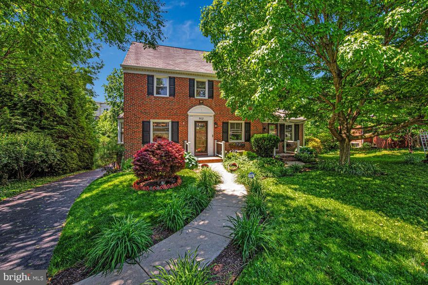 Welcome to 902 Locustvale Road — a character-rich brick colonial on a beautifully landscaped 0.35-acre lot in Towson's established Dulaney Manor neighborhood. Offered at $600,000, this 4BR, 3.5BA home delivers nearly 2,300 finished square feet, a fully finished lower level, and an attached garage — all framed by mature gardens and towering shade trees. Inside, gleaming hardwoods, crisp crown molding, and abundant natural light set the tone. The sun-filled living room is anchored by a classic brick fireplace and flows into a formal dining room ready for holidays and dinner parties alike.

At the heart of the home, the updated kitchen pairs white shaker cabinetry with stainless appliances, an electric range, farmhouse apron sink, tile backsplash, and a breakfast bar with pendant lighting. Just off the main living areas, step out to a true highlight — a covered flagstone porch topped by a brand-new custom awning, with wrought-iron railings overlooking the gardens. It's a private outdoor room you'll enjoy all season long.

Also on the main level, a fourth bedroom/secondary primary with a full bath offers exceptional flexibility — ideal for multi-generational living, in-laws, or guests who prefer single-level access. 

Upstairs, three additional bedrooms feature hardwoods, ceiling fans, and generous closets, including a bright, spacious primary and one with a bold floor-to-ceiling brick accent wall. The home's full baths have been tastefully refreshed with tiled walk-in showers, glass enclosures, and modern vanities. Above, a floored attic offers even more storage.

Downstairs, the fully finished lower level expands the home's livable space with a rec room, dedicated workshop, half bath, and laundry area, plus interior access to the attached garage — perfect for a gym, studio, or hangout space.

Outside, the deep, level yard is the standout — professionally landscaped with established beds, a graceful arbor, and mature-tree privacy on all sides. Recent peace-of-mind improvements include a CCTV-inspected, cleaned, and CIPP-relined sewer line and a new chimney cap. 

All of this in the heart of Towson — minutes from Towson Town Center, Towson University, Goucher College, GBMC, and Cromwell Valley Park, with quick access to I-695 and I-83. Timeless character, thoughtful updates, and an unbeatable setting — welcome home.