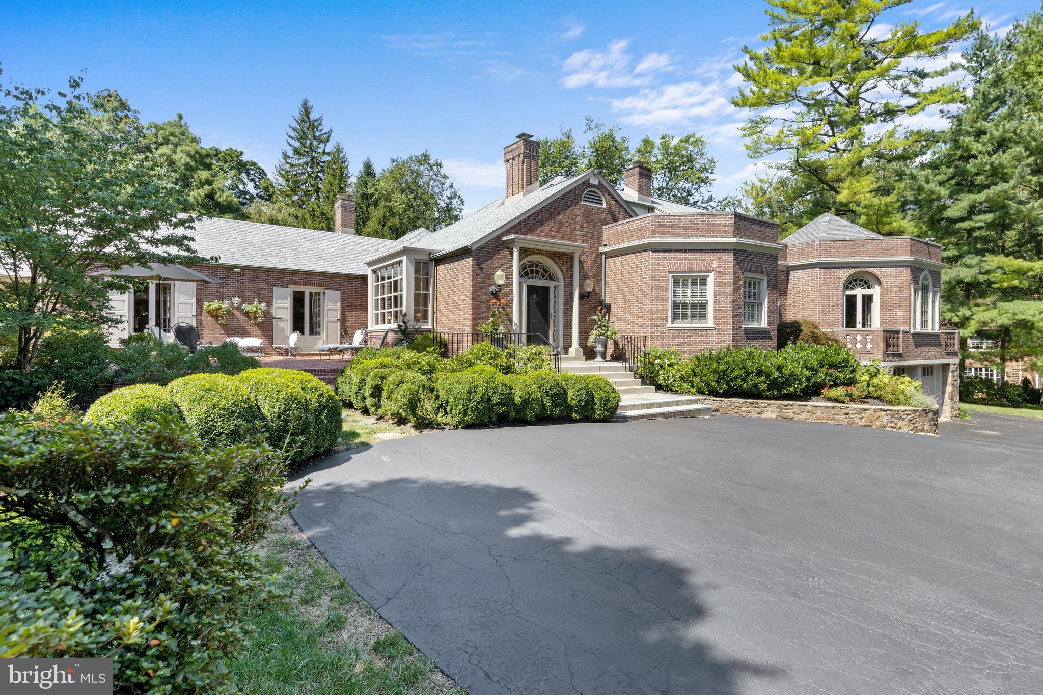 Welcome to 324 Keller Road, also known as "The House within a House." Originally built between 1907 & 1908 on nearly 200 acres as a summer home for a Philadelphia family until it changed hands in 1950. The home was then expanded to its present size and iconic brick exterior in 1951. Today's owners purchased the home more than 30 years ago and have since meticulously renovated and maintained this historic main line property. The stately, sweeping driveway is adorned in elegant mature landscaping that adds privacy and beauty at every turn. The driveway leads to an impressive front door trimmed in arched glass and surrounded by Flemish course brick exterior. Inside, "The Lobby" has greeted those who have entered for more that 70 years with soaring ceilings, an intricate stone fireplace/hearth, a wall of windows, hand crafted built-in bookshelves and more. "The Lobby" leads to a welcoming formal living room with gas fireplace, more built-ins and three large floor-to-ceiling French doors all spilling out on to an expansive brick patio, covered porch and side yard with stone walls. In addition, there is a large foyer and full bath on this wing. Back through "The Lobby" to enter the heart of the home with a front staircase and hallway to the formal dining room with French doors to another rear stone patio. The gourmet kitchen features a gathering island with gas range, built-in sub-zero fridge, a sink overlooking another rear flagstone patio. The nearby butler's pantry completes the kitchen. The breakfast room offers exposed brick wall, a desk and built-in cabinetry. The unique octagon family room will impress. Other features offered are a vaulted ceiling and more French doors to petite balconies with views of the front and side of home! The primary bedroom is on the main level with updated bathroom with heated floors, separate soaking tub and seamless shower. This room offers morning sun views with plantation shutters, built-in cabinetry and a large walk-in closet. The second bedroom sits opposite the hallway and offers another en-suite bath, closets and all day natural light. Outside the second bedroom find rear staircase to second floor. The "Entrance Worthy" main staircase reveals a gracious second floor hallway with built-in bookshelves and door to third en-suite bedroom. Opposite is a full walk-in attic with room to make this space all your own! Down the hallway is a fourth bedroom and a office/bonus room and a fifth bathroom. The lower level is large with attached two-car garage, lower level laundry room and another area of incredible space and storage. This historic home blends stately history with modern space and location. It's a one of a kind opportunity to own a perfect blend of history and modern amenities of the Mainline. Simply put, charm like this cannot be recreated today. This is an incredible home nestled along a quiet tree lined street in the popular Woodlea neighborhood. A short walk-to town, train, schools and more! Link to 3D tour - https://my.matterport.com/show/?m=mYMKRxTzFpg
