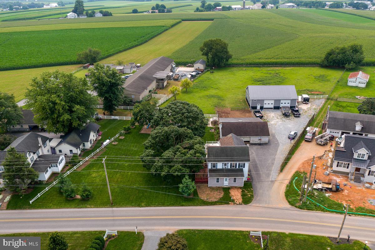 Auction with pre-auction offers considered. Auction scheduled for Wednesday, September 10 at 4:00 PM. This charming Lancaster County farmhouse offers the perfect blend of peaceful country living and functional versatility. Featuring five bedrooms (one with privacy violation) and 1.5 bathrooms, the home boasts a spacious layout ideal for multigenerational living or a growing household. The main level includes a large living room with a wood beam, a beautifully updated kitchen with two-tone cabinetry, gas cooking, counter with bar seating, and adjacent dining areas. You'll also find a bedroom, office, playroom, mudroom, pantry, and laundry room on the first floor, offering convenience and flexible space. Upstairs includes four additional bedrooms and access to a rooftop deck with scenic farmland views.
The outdoor living shines with a rear patio space for entertaining and a charming playground area tucked beneath mature trees. The fenced garden, greenhouse, and thoughtfully landscaped grounds are perfect for the hobby gardener. Equestrian and workshop needs are met with a 29x44 horse barn featuring four stalls and an 11x12 workshop, plus a 40x56 detached garage with two overhead doors, a 13x30 loft and separate 10x13 office. This property offers both lifestyle and utility in a peaceful, sought-after location close to Intercourse, Bird-in-Hand, Strasburg, and Route 30. Don’t miss this opportunity to own a spacious, well-kept property in the heart of Amish country. Pre-auction offers welcome!