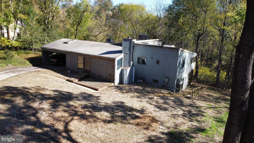 Listed significantly below market value (approximately $300k) to reflect immediate needs such as siding repair or replacement, bathroom repairs and more.  This property will not qualify for conventional financing. Buyers must be prepared for cash purchase, hard money loan, or renovation loan. Located in Howard County on 5+ acres, with top rated schools, this home is waiting to be restored to its original glory!  The home boasts a California-style center patio, accessible via multiple sliding glass doors, perfect for a fountain, Koi pond, or a two-tiered deck, with views of the wooded lot. Abundant natural light fills the home, featuring 6 skylights, angular windows flanking the living room fireplace, and 9 main-level sliding doors for seamless outdoor access. Dozens of dead trees were removed around the perimeter of the home to create more natural light into the home.  A versatile and stunning addition with four sliders and arched windows leading to the center patio can serve as a library, family room, or recreation room. It also includes a fireplace and two large windows.  The owner's suite offers direct access to a screened-in area overlooking the rear wooded yard. The owner's bathroom requires imagination and restoration.   Two additional spacious bedrooms are on the main level. One includes a wood-burning fireplace, a large bump-out window, and access to the center patio. The second bedroom is located at the rear of the home and connects to the screened-in area adjoining the owner's bedroom. The basement features an in-law suite with a full kitchen, a family room with stone flooring, and a side entry door. A fourth bedroom with an en-suite full bathroom are also on this level, with a screened-in porch accessible from the bedroom and family room.   Ducts were professionally cleaned, the newer HVAC system was recently serviced, and the well pump and storage tank are also newer.   Nearby comparable homes have recently sold in the mid-$800s, presenting a significant value proposition for the right buyer. This custom home offers a truly unique design and layout, awaiting a buyer with vision. Property sold "as-is".