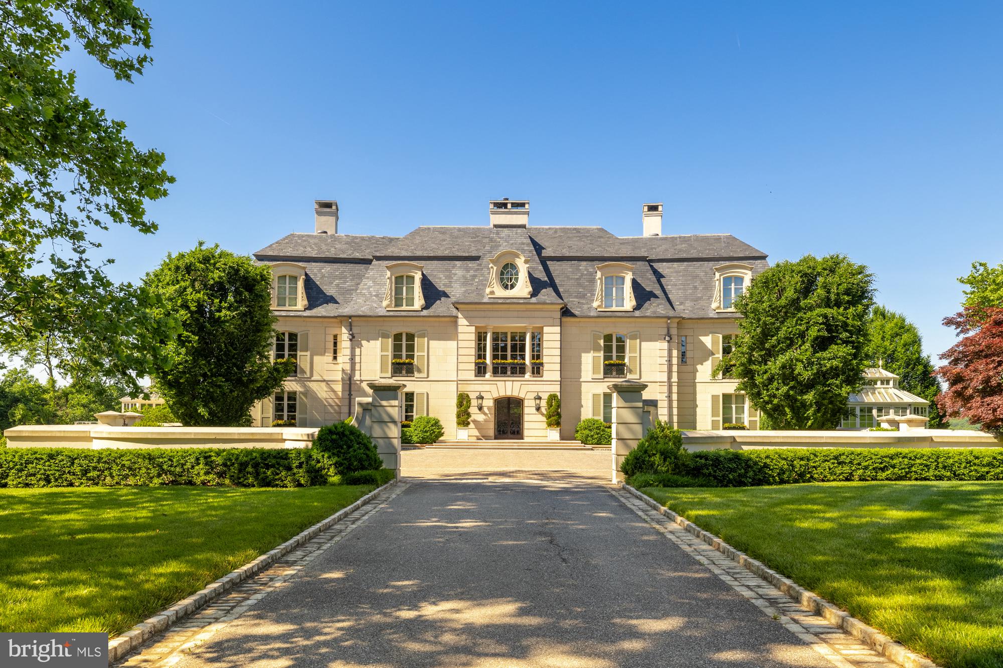 **$5,000,000 Price adjustment** Tucked discreetly behind an arched gate and approached by a half-mile avenue of trees, this 13.5 acre estate perfectly embodies the grandeur of French Chateau living. A masterful collaboration between architect John Ike, designer Geoffrey Bradfield & the unparalleled construction of Horizon Builders, the main house sits on a knoll with unobstructed views of the Potomac River and protected parkland on either side.
Wrapped in limestone and crowned with a slate Mansard roof, the primary residence features every hallmark of that iconic style; elegant and polished, but one that never competes with its breathtaking setting. Adorned with window boxes and decorative shutters, the timeless façade opens via custom wrought iron doors to a 25,000 sq foot interior where panoramic views are integrated into its soul. Simply stunning, the entry vestibule adjoins a reception hall with dramatic coffered ceilings, a 24-foot limestone fireplace, and a grand staircase. Floor-to-ceiling window expanses and multiple doors open to covered terraces and balconies that celebrate the surroundings. Lavish applications of glossy and honed marble, rich mahogany, thick, intricate moldings, and imported stone offer a glimpse of the detailing that went into the design and craftsmanship. At every turn, the water views effortlessly influence the design, while the elegant, understated palette provides the perfect backdrop for art and furnishings from antique to modern.
The primary residence is arranged over 4 levels that includes entertainment-sized reception rooms, a commercial-grade chef’s kitchen, main-level library, & an octagonal conservatory. The walk-out lower level is incredible, featuring a clubroom w/ a magnificent bar, a theater, & an amazing wine cellar that rivals those of the finest restaurants. An elevator accesses every floor. The main house also allows for the comfort and private enjoyment of the residents: with an intimate breakfast room overlooking the water, 4 luxuriously appointed upper-level bedroom suites, a custom playroom, and a heated pool and loggia. With sweeping views of the Potomac, the owner’s suite features 2 full baths, expansive automated dressing rooms, a built-in watch winder, & personal grooming station. The primary suite adjoins an executive-size home library, w/ a substantial marble fireplace & a surround of mahogany built-ins.
Comprising more than 40,000 square feet of living space, the compound includes two additional buildings that were crafted with the same meticulous attention to detail. A thoughtfully designed 3-level guesthouse with 11 garage bays presents the ultimate flexibility for the new owner; a showroom-style space for automobiles that effortlessly transforms into one that can host the most glamorous black-tie gala. and houses a catering kitchen. The upper level of the guesthouse offers a spacious gathering room w/ fireplace, 2 ensuite bedrooms, kitchen and powder room. A 4,500 square foot staff house is located at the entry to the compound & offers living space, multiple offices for property management & garages for the grounds equipment.
Every consideration for privacy, security and luxury has been incorporated into the infrastructure of this estate; there are walk-in refrigerators & freezers, reverse osmosis water systems, even smoke-eaters for the cigar aficionado. Generators protect all 3 structures, & in the event of winter weather, automated heating systems at the front steps & cobblestone garage court prevent snow/ice accumulation. All this convenient to the nation’s capital, 2 airports & less than 1.5 miles from Potomac Village. The transfer of title of this magnificent property doesn’t just extend to its new owner but will have an immeasurable impact far outside its gates; the proceeds from the sale will be donated directly to the research and work of The American Cancer Society. The Estate at River's Edge is truly like no other.