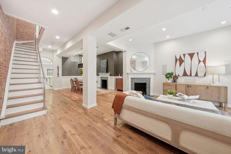 This rare and expansive four-story rowhome is among the largest historic residences on sought-after Westminster Street NW. Blending timeless character with modern luxury, it offers generous indoor and outdoor living spaces, sophisticated finishes, and an enviable location. Step through a gracious double-door vestibule into an open living and dining area, where exposed brick walls and two glass-tile fireplaces create a warm, contemporary feel. Refinished white oak floors extend throughout the home, while a fully integrated three-floor audio system and dual-zone Nest-controlled HVAC add comfort and convenience. The showpiece of this level is the 25' x 12' chef’s kitchen, designed for entertaining. It features a professional six-burner range with griddle and double oven beneath a commercial hood, plus an oversized 34" refrigerator and matching freezer. A substantial island with seating for five complements the space, leaving room for a breakfast table. At the rear, a secure 18.8' x 18.7' parking pad provides easy access. The second floor includes a south-facing bedroom suite, as large as the primary suite, offering a cozy reading nook, en-suite bath, and walk-in closet with ELFA shelving (a feature shared across all bedroom closets). A second bedroom opens to a private balcony, while a third is ideal for a home office or nursery. A hall bath with soaking tub completes the floor.  The third floor primary suite is a private retreat, featuring two double-door closets, a Juliet balcony and a spa-inspired bath with dual vanities, soaking tub, and a multi-head frameless glass shower. This level also includes a powder room and wet bar with wine fridge, prep sink, and ice maker—perfect for entertaining on the expansive 14' x 24' terrace. From here, a spiral staircase leads to an 18' x 24' rooftop sundeck with sweeping 360° views of DC, including the Washington Monument. In all, the home offers over 800 sq. ft. of above-grade outdoor living space. The fully finished lower-level functions as a separate two-bedroom, one-bath apartment, ideal for guests, an au pair, or rental income (most recently leased for $2,995/month). Nestled just steps from Westminster Park, the home is within easy reach of Shaw and Logan Circle’s acclaimed dining, shopping, and conveniences—including Whole Foods and Trader Joe’s.