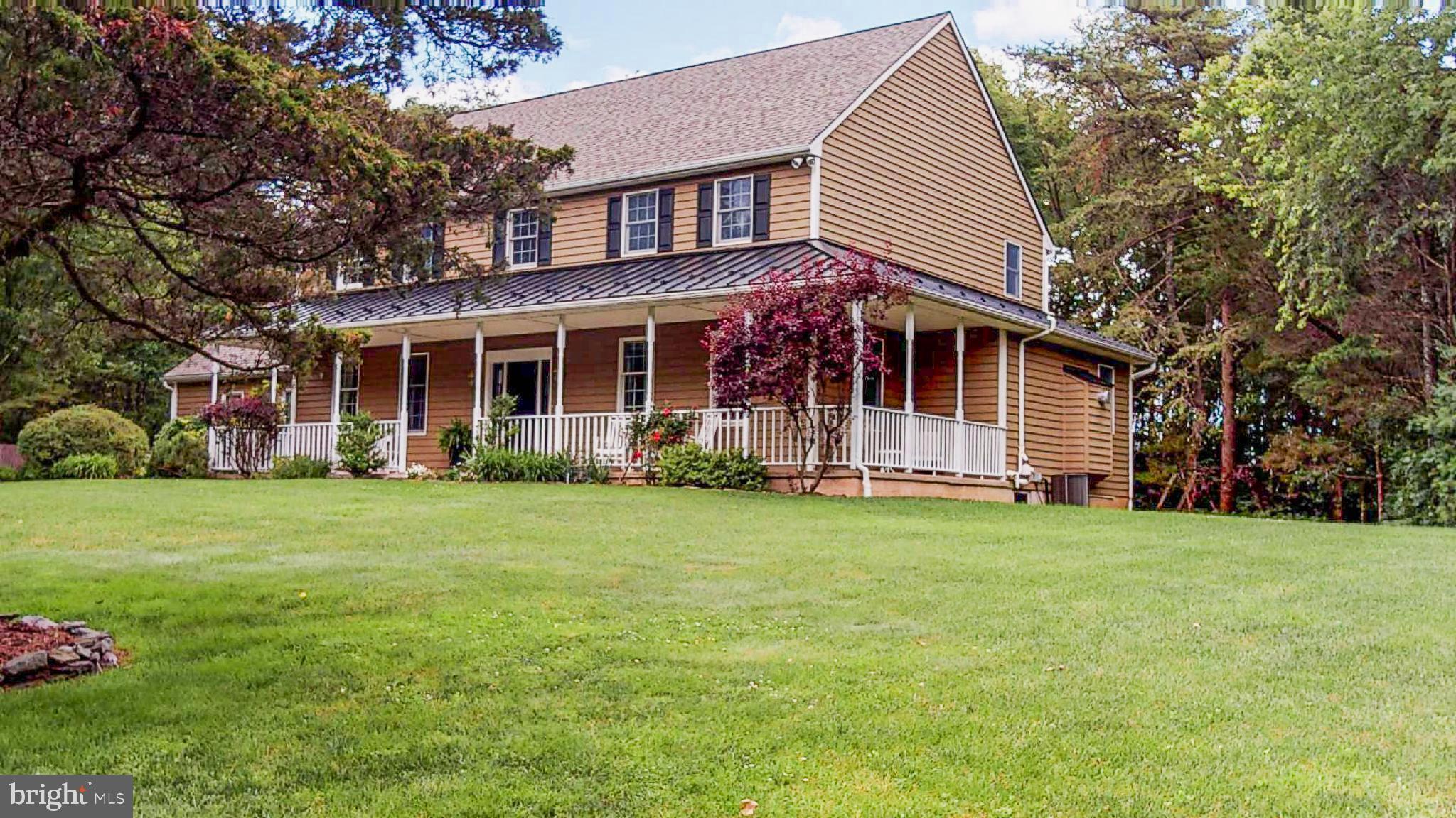 MOTIVATED SELLER.  Privacy and seclusion is realized when you follow the long and winding driveway through the wooded yard that opens up to this custom-built colonial farmhouse with covered wrap-around front porch. First floor features include a renovated/upgraded kitchen with custom cherry cabinets, center island with gas cooktop, wall oven and built in microwave adjacent to a desk area, all with Corian countertops that opens into an eating area with French doors that leads to the outside deck. The large tiled kitchen also opens to a family room with a gas fireplace and custom built-ins.  The first floor has a  large formal dining room with hardwood floors, a living room, half-bathroom and a separate mudroom with pantry. On the second floor, the master bedroom has a newly renovated master bath and a balcony overlooking the wooded back yard providing total privacy and a tranquil place to view the abundant wildlife and enjoy morning coffee.  Four additional bedrooms, a full bath and laundry room complete the second floor.  The basement is partially finished and includes a rec-room, along with a  full bath and spare room adding an additional 698 Sq Ft. Above the attached 2-car garage is a finished bonus room with separate outside entrance and stairs that could be used for a potential home business or tele-commuting. This property also includes a separate detached (25x28) garage and workshop building for plenty of storage and home projects. All of this is surrounded by a private yard that has been meticulously maintained and includes several rock gardens, fern gardens, flower gardens, and secluded walking trails that meander through the entire 2+ acres. Home wired for backup generator, exterior video & record camera and security system. This home is in exceptional condition and offers a great chance for any one to enjoy privacy and nature in the middle of Montgomery County. All rooms are approximate in size.