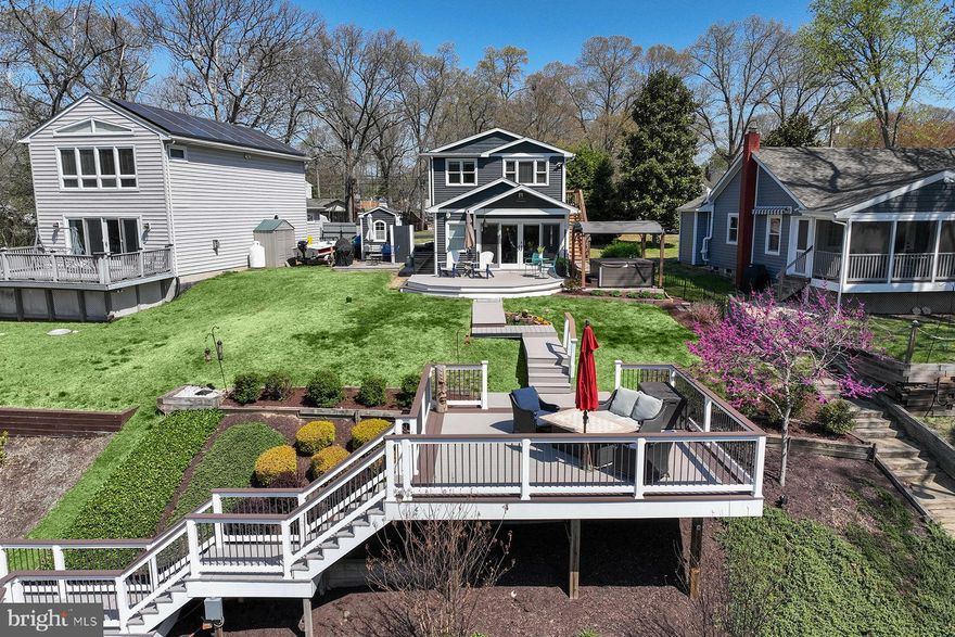 Welcome to this stunning, fully rebuilt (2021) waterfront property on the Magothy River —where thoughtful design meets effortless Chesapeake Bay living. With 3 bedrooms and 2.5 baths, this home blends modern coastal finishes such as luxury vinyl plank flooring with timeless comfort across a bright, open layout. The waterfront amenities are super: large deck overlooking the creek, private pier with 6 ft water depth and a 10,000 lb lift, and a grassy waterside yard that's perfect for a picnic and small boat storage. Take your boat for a quick ride down the river to have lunch at The Point.
The heart of the home is the great room, including the gourmet kitchen, with a custom tile backsplash, soft-close drawers, farmhouse sink, stainless steel appliances, a beverage fridge, and a custom wood-topped bar area. Here, the coastal design elements are effortless yet sophisticated. Contemporary light fixtures add a stylish touch, while the oversized island offers both functionality and a perfect spot for gathering. The kitchen opens seamlessly to the seating area with its stunning shiplap vaulted ceiling, eye-catching wooden ceiling fan, and doors that open directly to the waterside deck. There are two decks to enjoy outside, one just outside the great room and the other overlooking the water. The main level also includes a dining room with fabulous chandelier, mudroom, and powder room.
The primary suite is a serene escape with a private seating area overlooking the river, large walk-in closet and a spa-like, ensuite bath. Enjoy separate sinks, a walk-in shower with multiple shower heads and a built-in bench, and natural stone flooring for that luxurious, spa-inspired feel. There are two more bedrooms, both bright and sunny, with the same LVP flooring. They share the hall bathroom upstairs. The fully finished lower level has the laundry room and offers flexible living space for a home theater, rec room, home office, or gym.