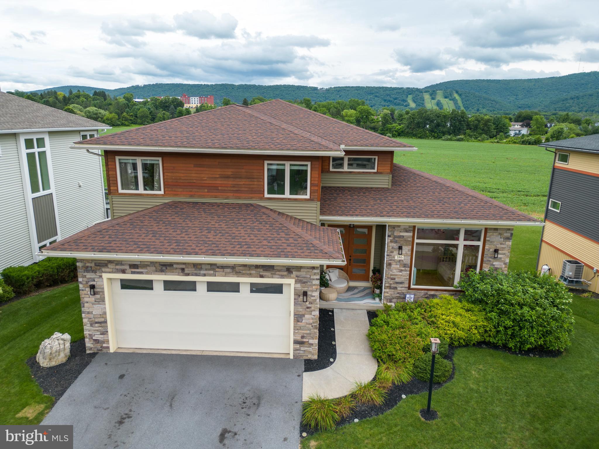 Designed to impress, this stunning home in the desirable Rockey Ridge development delivers an elevated living experience with breathtaking views of Tussey Mountain from every angle. Be welcomed by the expansive, light-filled interiors and soaring ceilings.
Entertain in grandeur beneath chandeliers in the dramatic two-story dining room, or prepare gourmet meals in the exquisite chef’s kitchen—designed for both intimate dinners and lively gatherings. The main level family room invites relaxation with its warm fireplace, while the walkout lower level rec room is a destination of its own, featuring a full bar, wall to wall windows, and effortless flow to the outdoors.
Upstairs, the primary suite is a true sanctuary, complete with a spa inspired bath where you can unwind in tranquility. With four spacious bedrooms, a versatile office or den, and a fully finished basement, this home offers room to grow, host, and recharge.
Step outside to experience your private outdoor oasis, an expansive flat backyard with a custom fire pit area, hot tub, exterior TV mount, and multiple entertaining spaces including a large deck and walkout patio, all perfectly positioned to capture the breathtaking mountain backdrop. Enjoy the thoughtful craftsmanship and refined luxury that make this home truly exceptional, make it yours today!