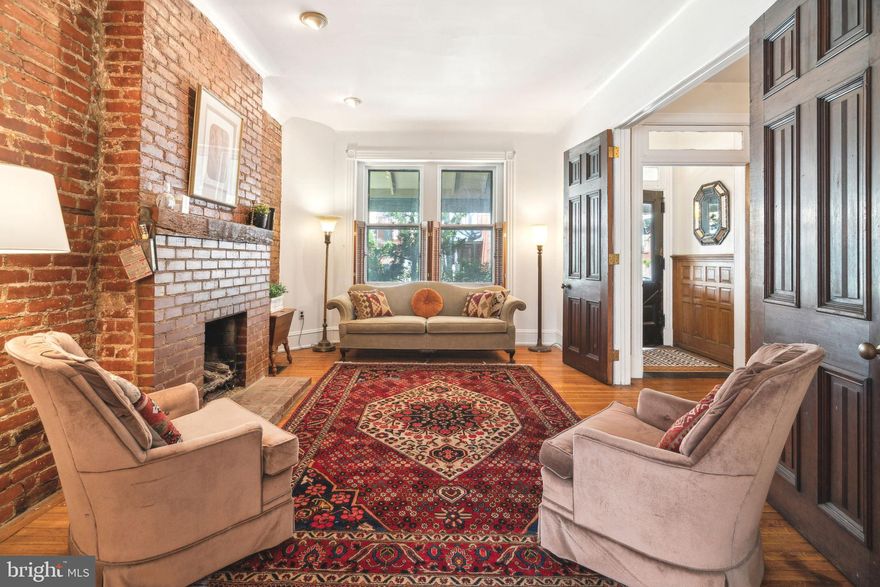 Classic porch-front Victorian twin on one of Cedar Park’s favorite blocks. Lined with mature trees and festooned with string lights between the houses, this friendly, intimate street is just one block long and sees little through traffic. From the generous front porch, enter through the double-door vestibule—featuring wood paneling and original tiled flooring—into a wide staircase hallway. A pair of oak doors leads into the front parlor, where high ceilings and an exposed brick wall with a gas fireplace create a welcoming focal point. Original oak pocket doors connect to the formal dining room, which features a bay window, hardwood floors, and a leaded glass door to the hallway. Just beyond, the spacious eat-in kitchen offers an island counter, an exposed brick wall, and direct access to a deep backyard—perfect for gardening, barbecues, and outdoor gatherings. Upstairs on the second floor, the large primary suite (currently used as a sitting room) includes bay windows, excellent closet space, and a pass-through to a second room ideal as a dressing room or nursery. A standard three-piece ensuite tiled bath completes the suite. At the end of the hall, a third bedroom offers another ensuite bathroom with a stall shower and backyard views. The third floor features two additional bedrooms (one currently used as another sitting room), a full bathroom, a skylight, and a second kitchen—providing flexibility for a guest or in-law suite. A large attic space offers potential to be finished as a playroom or serves as endless storage. The full basement houses the home’s mechanical systems and includes Bilco doors leading to the backyard. Throughout the home, original wood details are beautifully preserved, and all bedrooms offer excellent closet space. Located just steps from Clark Park and the Baltimore Avenue corridor—with international cuisine at beloved local favorites like Doro Bet, Gold Standard, Loco Pez, Vietnam Café, and Dahlak—and offering easy access to UPenn, CHOP, HUP, St. Joe’s, University of the Sciences, and Drexel, this location is a walker’s and biker’s paradise with excellent transit options including the trolley and SEPTA. This is a home that blends timeless charm with everyday convenience in one of West Philadelphia’s most welcoming communities—come see it today!