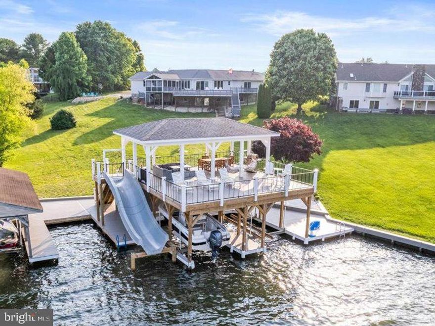 Resort style living in this gorgeous Lake Anna retreat located on the public side of the lake. High Speed Fiber internet! You'll love the two story, state-of-the-art boathouse that features your own personal water slide with running water, two covered boat slips with electric lifts, storage room, sun deck, partially covered upper deck to lounge and entertain on with a ceiling fan, smart TV & fridge, along with unparalleled views of Lake Anna.  Nestled on a No Wake Cove, with your own private sandy beach, it's the perfect place for swimming or floating in the water. Relax in over 3,300 finished square feet with million dollar views and many recent improvements. 7 bedrooms, 4 full baths and an open floor plan. Beautiful vaulted shiplap ceilings, custom wood barn door, gas fireplace, LVP flooring, new quartz countertops, professionally painted kitchen cabinets and fresh paint throughout the entire home. Main level primary en suite features a walk-in closet and a door to the back deck that overlooks the water. There are two additional main level bedrooms and a full bath. Fully finished walkout lower level features a family room, gas fireplace, rec room, one en suite bedroom, 3 bedrooms and a full bath. Newly renovated garage converted to a game room with its own slide provides even more options for entertaining! Huge back deck & a spacious screened in porch with ceiling fan all overlooking the lake. Gather around the fire pit or play a game of basketball with your family & friends! This home is currently a successful Short Term Rental and rentals can convey if you wish! Great lake location close to Elk Creek Country Store & gas station, Lake Anna Taphouse, local dining, vet clinic & New Bridge Landing Shopping Center, where you'll find groceries, ABC, Verizon store, a nail salon, and more. Schedule your tour today; this one will blow you away. Furniture negotiable. See MLS documents section for furniture information, list of improvements, and rental info. It has $93,933.00 in future rentals on the calendar as of 8/21/2023 making it the perfect investment property! Property was just professionally landscaped!