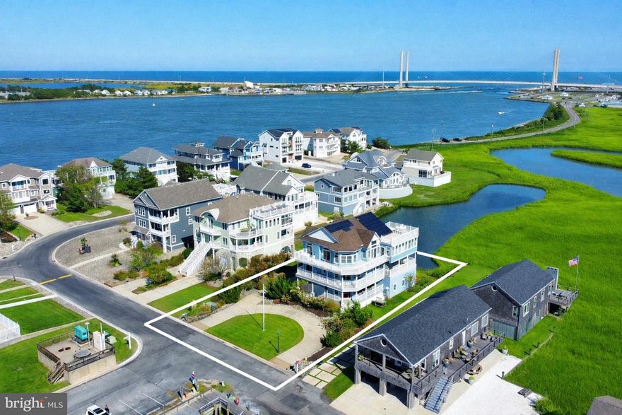 Extraordinary bayfront retreat offering sweeping, unobstructed views of the open bay and the private community marina. Thoughtfully designed with an inverted floor plan, this residence maximizes its stunning vistas from every room. The impressive great room features soaring ceilings, rich hardwood floors, and a sleek gas fireplace framed by a dramatic floor-to-ceiling stone surround. The open layout flows effortlessly into the dining and kitchen areas—perfect for entertaining or relaxed coastal living. The kitchen showcases quartz countertops, an expansive center island with seating, crisp white cabinetry, a beautifully tiled backsplash, and premium stainless steel appliances. Sliding glass doors lead to an oversized sunroom that serves as an inviting second living space with panoramic water views. Also on this upper level, the primary suite is a serene retreat with a luxurious spa-like bath featuring dual sinks, a jetted tub, and a glass-enclosed walk-in shower. The middle level hosts four spacious bedrooms—two with private en suite baths and two connected by a stylish Jack and Jill bath—providing comfort and privacy for family and guests alike. Completely renovated with fine finishes and thoughtful details throughout, this exceptional home offers modern conveniences including an elevator, over sized garage with an office, hurricane shutters, solar panels, and a whole-house generator. Expansive wraparound porches on every level and a large rooftop deck invite you to relax and savor the coastal breeze. Located in a prestigious gated bayfront community in North Bethany with amenities including a deep-water marina, pool, and tennis courts. Spend the day boating with direct access to the Indian River Inlet or enjoy the beach—just a short bike ride away—without crossing Route One.