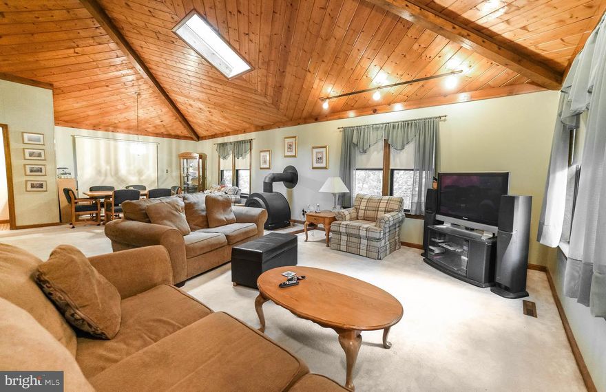 Cool contemporary is WAY bigger than it looks--new price provides great value for your $$! You'll love the vaulted wood ceiling with skylights over the great room, with lots of open space to design your way. Efficient kitchen has breakfast bar and nice appliances. Dining area has new hardwood floor; kitchen has new vinyl. Two sliders to the wraparound deck on the main level make for easy entertaining. Wood stove heats everything in the winter! Lower level houses all four bedrooms; master has separate vanity/sink, plus full attached bath w/tiled shower and two walk-in closets. Hall bath with ceramic tile, 3 more bedrooms, and laundry room complete the lower level. Deck backs to trees for peace and privacy! Wildewood offers walk/jog lanes and recreation area, and pool memberships are available. Close to shopping, and Evergreen Elementary is in the neighborhood!