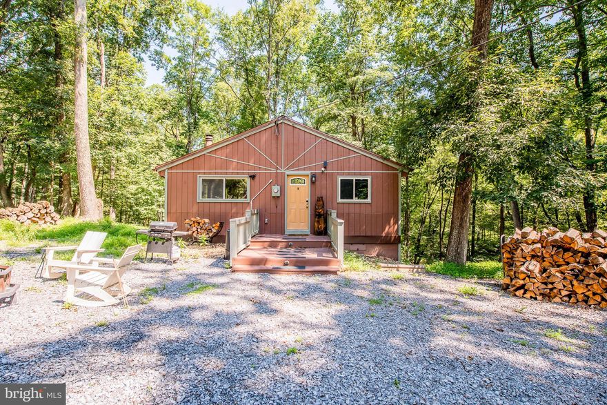 Welcome to Wild Creek Cabin, an adorable and cozy retreat nestled on just under an acre in The Woods Resort. This charming property has been successfully used as a short-term rental, offering an excellent opportunity for personal enjoyment or as an income-generating retreat. 

Featuring 2 bedrooms and 1 full bath, the kitchen offers granite countertops, a black appliance package, updated lighting, luxury vinyl plank flooring throughout, and rough-sawn lumber accent walls. The living area includes a beautifully white-washed painted brick wood-burning fireplace. This home also offers a screened back porch overlooking a backyard stream that has been reengineered and reinforced to accommodate a new hot tub, complete with a tin ceiling, ceiling fan, and a hot water tap installed for easy hot tub filling and cleaning. A new stackable washer and dryer has also been added. Additional exterior improvements include a widened new driveway, new culvert, additional parking area, fresh gravel, and approximately 30 trees cleared to enhance views and safety. Recent upgrades include an architectural shingle roof, dual-zoned mini-split system, and vinyl windows. 

This property offers a Class B Membership, available with a $3,150 initiation fee and annual club dues of $1,600. Please note, private club amenities are not owned or operated by the HOA. Membership includes access to an indoor fitness center featuring racquetball, gym, indoor pool, sauna, whirlpool, indoor/outdoor tennis, basketball, shuffleboard, and pickleball courts, plus two outdoor pools, a clubhouse, and fishing ponds. Wild Creek Cabin offers year-round enjoyment, whether you’re soaking in the hot tub after a day of hiking, enjoying quiet mornings with coffee on the screened porch, or unwinding by the warm wood-burning fireplace on crisp evenings. Thoughtfully updated and well cared for, this cabin combines rustic charm with modern comfort. Whether you’re seeking a peaceful personal getaway or a profitable short-term rental investment, this inviting property is ready to welcome its next owner. Schedule your private showing today and experience all that The Woods Resort has to offer.