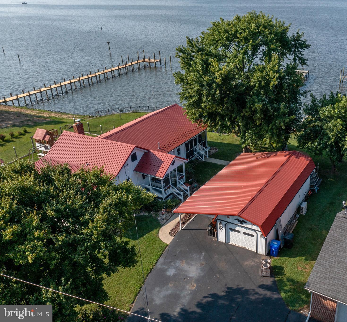 Beautiful waterfront home on a half acre with private pier! Enjoy the scenic views and breathtaking sunsets year round. The house has been tastefully updated over the years to include LVP flooring throughout, updated bathrooms with tile, updated kitchen with granite countertops. The family room has a built in entertainment center and book shelves with cabinetry and a wood burning fireplace. Separate laundry room with shelving. Covered side porch with main entrance to the house. The large screened in porch has a new ceiling, screens and screen underneath to keep the bugs out which is perfect for your morning coffee, eating crabs or dinner with the family. The detached garage was converted into a "man cave" complete with black bamboo flooring and a projection screen. Sliding doors from the man cave lead out to a custom built Tiki bar with full size fridge and kegerator. There is a retracting door that pulls down to protect the bar from the elements when not in use. Deck with built in benches and pub table attached to the Tiki bar provide additional seating. Covered carport with space for 3 cars. Back section of the garage has room for storage and there is 10 x 12 shed for additional storage. Expansive river views with 110 ft of water frontage with bulk head and braced sea wall. Stone retaining wall in front of the house with steps leading down. The lot is partially fenced in on the side with nice level area. Enjoy fishing or crabbing off the pier, swimming, kayaking or boating. Fire pit for bon fires at night. This beauty will not last long. Schedule your showing today!
Professional pictures to follow.