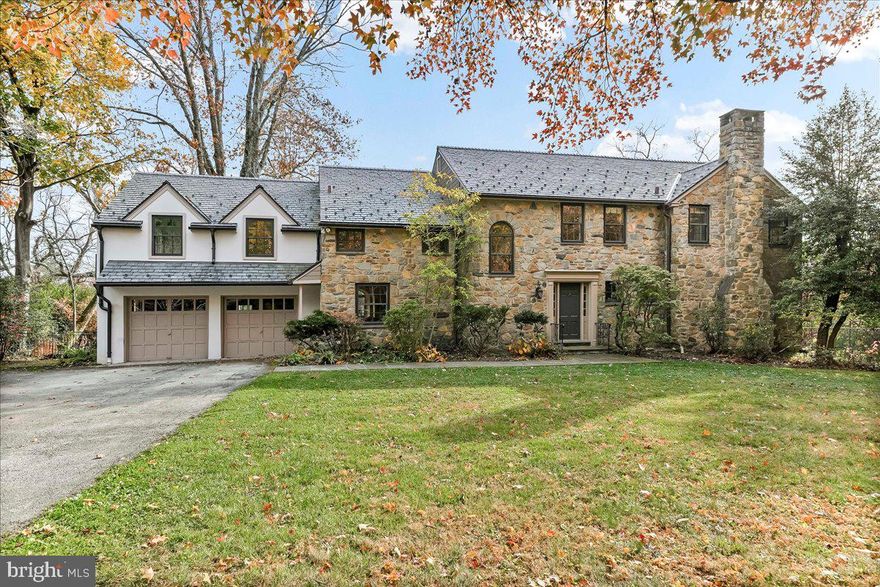 Surrounded by curated natural beauty and just moments from Dove Lake, this classic 1950s Main Line residence blends privacy, convenience, and timeless character in one of Gladwyne’s most desirable cul-de-sac settings. The stately stone exterior, enhanced by a new Vermont ¾-inch slate roof (2023), is set on nearly one acre of sweeping lawn and mature landscaping.  723 Dixon Lane offers 4,049 square feet across two levels with four to five bedrooms and four-and-a-half baths.  A stone walkway leads to the front entry and welcoming foyer, flanked by a powder room and large coat closet. The home was thoughtfully designed to allow for a future full elevator here if desired.  The main level features gracious, light-filled gathering spaces where old-world charm meets refined architectural detail. The dining room is framed by intricate mouldings and overlooks the serene rear grounds. All wallpaper and paint on this level are Farrow & Ball. A door from the dining room opens to the enclosed bluestone terrace with two skylights and a new metal roof (2023), offering an elevated vantage point over the heated pool (gas), gardens, and tennis court. Expansive windows throughout this level bring in exceptional natural light.  A cozy den with built-ins provides an intimate retreat, while directly across the hall, a sophisticated prohibition-era bar showcases lighted glass shelving and dark wood cabinetry. The living room features hardwood floors, deep window sills, built-ins, and a paneled fireplace surround. A door from the living room opens directly onto the enclosed terrace, creating seamless indoor-outdoor flow.  The custom eat-in kitchen sits just off the dining room and features Signature Cabinetry with soft-close drawers, paneled Sub-Zero refrigerator, six-burner Wolf stove with Best stainless-steel hood, double ovens, a large center island with undermount stainless sink, granite countertops, breakfast nook, pantry, built-in desk area, and rear mudroom. This back area also includes two rear staircases, offering excellent functionality and layout flexibility.  Upstairs, the expansive primary suite occupies an entire side of the home. The sitting room can serve as a private office or be converted to a fifth bedroom. The spacious bedroom overlooks the grounds and includes extensive, lighted walk-in closets with custom designed built-ins with bench seating. The spa-like bath features two large vanities, a luxurious soaking tub, private water closet, and walk-in steam shower with bench seating. Farrow & Ball paint continues throughout this level. Bedroom three has a private hall bath, while bedroom four includes its own en-suite bath and walk-in closet. A newer addition above the garage offers a fifth bedroom suite with en-suite bathroom, LVP flooring, new Marvin windows and French doors, a separately zoned thermostat and heat pump (controls both heat and A/C), custom kitchenette with Pietra del Cardosa granite countertops, lounge area and a custom-made by Metalmorphose wrought-iron balcony overlooking the grounds. Perfect for guests, an au pair, or an in-law suite. All carpeted rooms have hardwood flooring beneath. The 1,000+ square-foot finished walk-out lower level includes radiant hydronic floors supplied by a newly installed Bradford-White hot water heater, paneled walls, a five-person sauna, full bathroom, wine cellar, dark room, recreation room, linen/china/storage room and mechanical room with NEW 5-stage inverter, variable speed Carrier A/C (2024) with 10-year warranty and Gas Heater (2019).  Outdoor amenities include a heated pool with bluestone patio, a second terraced bluestone dining area, tennis court, shed, gardens, and expansive lawns bordered by mature landscaping, creating a truly picturesque setting. Enduring architecture and distinguished spaces, this remarkable home is ready to welcome its next owner.