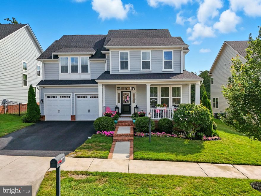 The highly sought-after Berkeley floorplan is perfectly positioned on a cul-de-sac street backing to trees and a seasonal view of the only Jack Nicklaus-designed course in Northern Virginia. Designed with functionality in mind, it offers a warm, welcoming classic floor plan. A charming full-width front porch invites you into the open foyer, with a dedicated office to the right of the entrance. Then, you pass by the formal dining room, perfect for entertaining.
You will stop and pause in the kitchen. It is simply beautiful with a massive center island, and wrap-around granite counter space with lots of drawers and cabinets to the ceiling with glass doors. ( You won't be disappointed!) And the family room is one of the largest in the community, and the owners added a 4-foot extension, creating an impressive gathering space! Access the rear covered porch and patio from the kitchen, extending your entertaining and living space to the outdoors.  Note the rear foyer and a half bath lead to the garage entry. Head upstairs and you will find four well-appointed bedrooms. The owner's suite is large,  with lots of windows, and a luxury bath with tub and free-standing shower, double sinks, and a huge walk-in closet. At the end of the hall, you will find a large walk-in laundry. The other three bedrooms, one of which is an ensuite, and the other two share the hall bath. Head downstairs to the finished lower level and you will find a 1200+ sq ft space equipped with a large, beautiful, upgraded wet bar which is designed for entertaining to the fullest, or find a finished LARGE bedroom for relaxing, as well as a large storage area.
Now for some of the features of this home. It has 9-foot Ceilings, 6 Ceiling fans, Gas Heat, a gas five-burner cooktop, a gas water heater, a Lawn Sprinkler, low-e-lite windows, and the house was built with James Hardie Siding and a full-house Fire Suppression System. These last three help lower the cost of your homeowners insurance policy. ( So make sure you tell the Insurance Company when you order your insurance!) There's more. Potomac Shores residents pay $180 for HOA fees. The HOA fees include high-speed internet and trash service as well as access to The Shores Club, featuring 13,000 sq ft of recreation and entertainment spaces, including a full-size gym, pools, movement rooms, community gardens, event lawn, and so much more. There is a second event space and pool complex off River Heritage Blvd. The social committee hosts events for the entire community throughout the year. There is also a schedule of Events, classes, and Meet-ups. Think Caskers Club, Beer & Wine Club, Book Clubs,  Paint & Sip, Education Meet-ups, and things for all ages. Potomac Shores is also home to an extensive trails system suitable for hiking and biking, and not to be missed.  You're not just buying a home, you are buying into a lifestyle.
Potomac Shores will have a VRE Station and a day-to-night town center in the future; both areas have started. There is a new Central Park Event area just below the town center area. Ask any question you like. We know Potomac Shores! VA Assumable possible call for details.