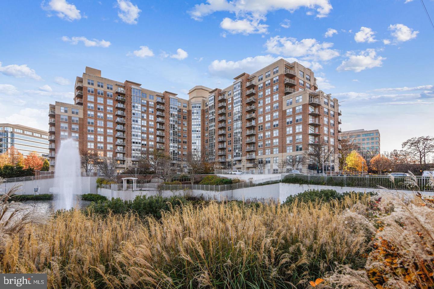 Sun-filled penthouse-level 1BR condo just steps from Reston Town Center, the Metro, Whole Foods, shops, dining, and more. This well-maintained unit features 11-foot ceilings, floor-to-ceiling windows in the living room, wood floors in the living area and bedroom, and an open kitchen with granite countertops, maple cabinets, and stainless steel appliances. The bedroom includes a walk-in closet with an Elfa storage system, and there is a stacked washer and dryer in-unit, plus a tankless water heater.
Located in the Carlton House, amenities include a secure entry with front desk concierge, media room, business center with free printing, fitness center with snack bar, rooftop club room, billiards room, pool, and terrace with gas grill. One garage parking space included, along with plenty of visitor parking. Easy access to the Toll Road, Rt 7, Tysons Corner, Dulles Airport, and Washington, DC. The Washington & Old Dominion Trail is just outside the building. The unit has been freshly painted in a lighter tone—new photos coming next week.