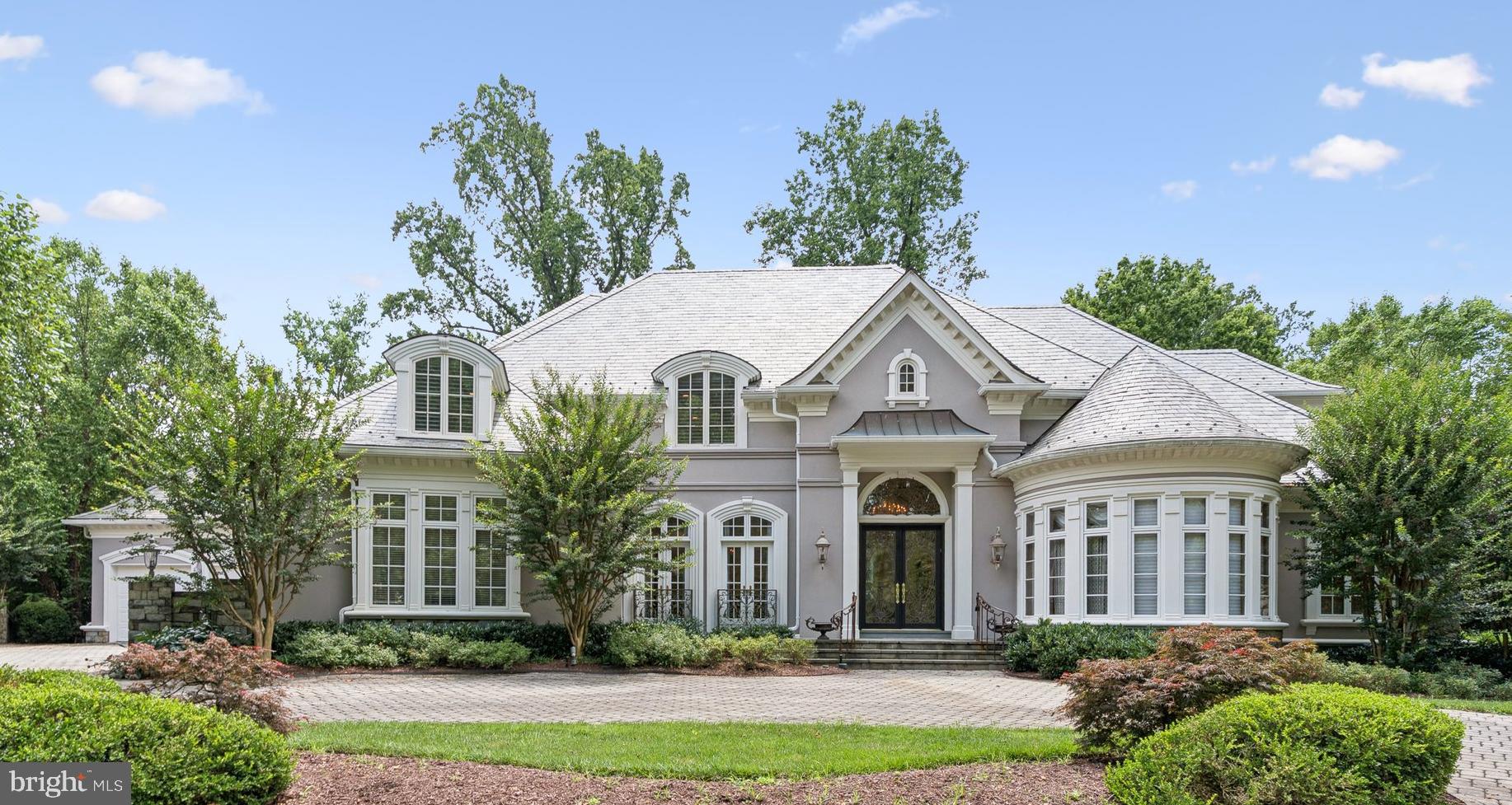 Located within the quiet gated community of Rapley Preserve at Avenel, this custom-built 11,000 square foot oasis elevates the concept of luxury living to an entirely new level. Classic slate roofing, arched windows, plaster crown moldings and applications of glass and hand-crafted scrolled ironwork set the tone of refined elegance that begins at the custom front door and extends through all three levels. Extensively renovated in 2023, the home's exquisite woodwork, new wide plank white oak hardwood floors, polished marble and multi-story windows provide the architectural framework for a home that presents the perfect canvas for traditional or modern furnishings and art. There are 5 bedroom suites, including the main level primary, 5 full and 3 half baths. The main level features a handsome paneled library with curved wall of windows and fireplace, a beautiful formal dining room with hand-painted wallpaper, a living room defined by a stunning floor-to-ceiling palladian window, and formal and informal powder rooms. The kitchen is every chef’s dream, appointed with vaulted, beamed wood ceiling, limestone ceramic floors, and a substantial marble-topped island. The open concept kitchen/family room offers a sunlit casual dining area overlooking the grounds and the family room is enhanced with built-ins and one of the home’s 5 fireplaces. Every fireplace is dual fuel, operable as wood burning or gas. Sited for privacy at the opposite end of the main level, the primary suite includes three professionally organized walk-in closets including a custom dressing room, gorgeous bath with octagonal tray ceiling, a personal home office space, and an exercise room. The bedroom space is expansive but so inviting, overlooking the lush backyard. A work of art itself, the dramatic scrolled stair banister to the upper level, one of two staircases, leads to 3 additional ensuite bedrooms, each with a renovated bath. The bedrooms all feature ample space for furnishings and include large closets. The sprawling lower level introduces a host of entertaining areas. Perfect for home movie nights, a household looking for play space or one with frequent overnight guests, there are four spacious recreation/leisure rooms, two more fireplaces, a 5th ensuite bedroom and walk up access to the grounds. The infrastructure is equally impressive with abundant storage space, multiple zoned heat and cooling, a reverse osmosis water system with UV filtration, and 4 garage spaces that are tucked discreetly to the side of the property. Set on a .71-acre lot, this beautiful residence fronts the scenic parkland of Rapley Preserve and features a flagstone patio with multiple seating and dining areas overlooking the meticulously landscaped backyard. Centered around the professional TPC golf course of Potomac, Avenel includes three swimming pools, a clubhouse, tennis and pickleball courts, ball fields and playgrounds, and a three-mile jogging and biking trail. Many homes in the community have private pools, and this property presents that option to the new owner as well. HOA includes all lawn care. Offering the turn-key luxury lifestyle for which Avenel is renowned, this residence is truly a celebration of style and substance.