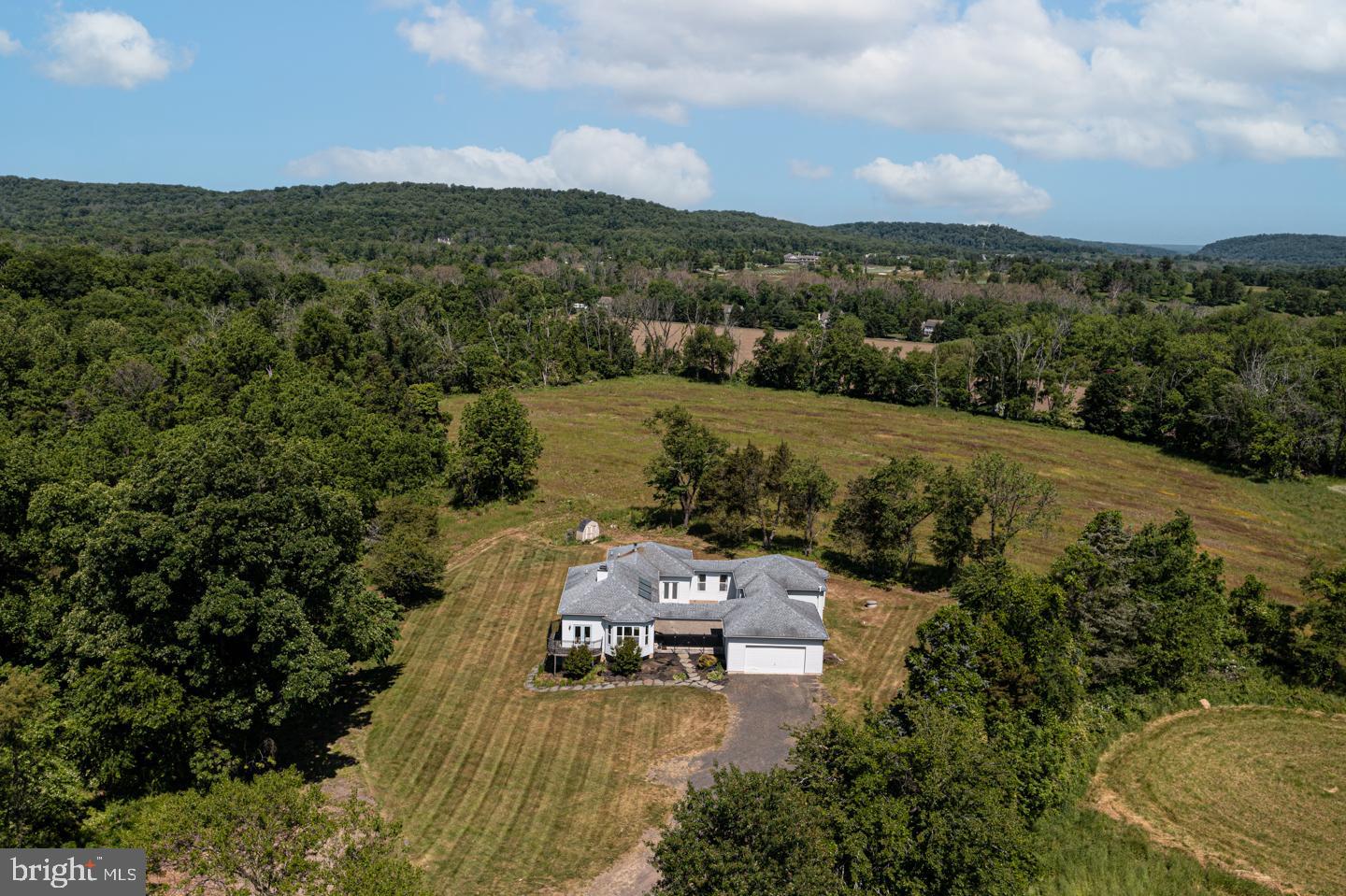 Calling all nature lovers! This charming rambling ranch home in Upper Makefield is in a picture-perfect setting! Situated on a large, 3 acre lot with amazing long-distance views, nestled among farmland, it will appeal to the nature-lover in all of us. Private and set back off the road, this spacious, 3-bedroom home is a fantastic one-floor living opportunity, offering wonderful open space and a great flow for entertaining and everyday life. Featuring an open layout, the gathering room opens to the kitchen anchored by a breakfast area, double sided fireplace and leads to a covered deck. The primary bedroom is contained on a wing of its own with a large private bath, mudroom and an entrance connected to the 2 car garage. Two additional bedrooms share an updated hall bath and spacious living area. This home has vaulted ceilings, French doors and plenty of windows, creating an open and airy feel while filling it with an abundance of natural light and views of the peaceful farmland. Most rooms exit to a large, central courtyard with a lovely, versatile design. The walkout lower level is unfinished and offers unlimited possibilities with roughed in plumbing and fantastic storage. Bring your vision! Don’t miss this amazing opportunity in Council Rock North schools.