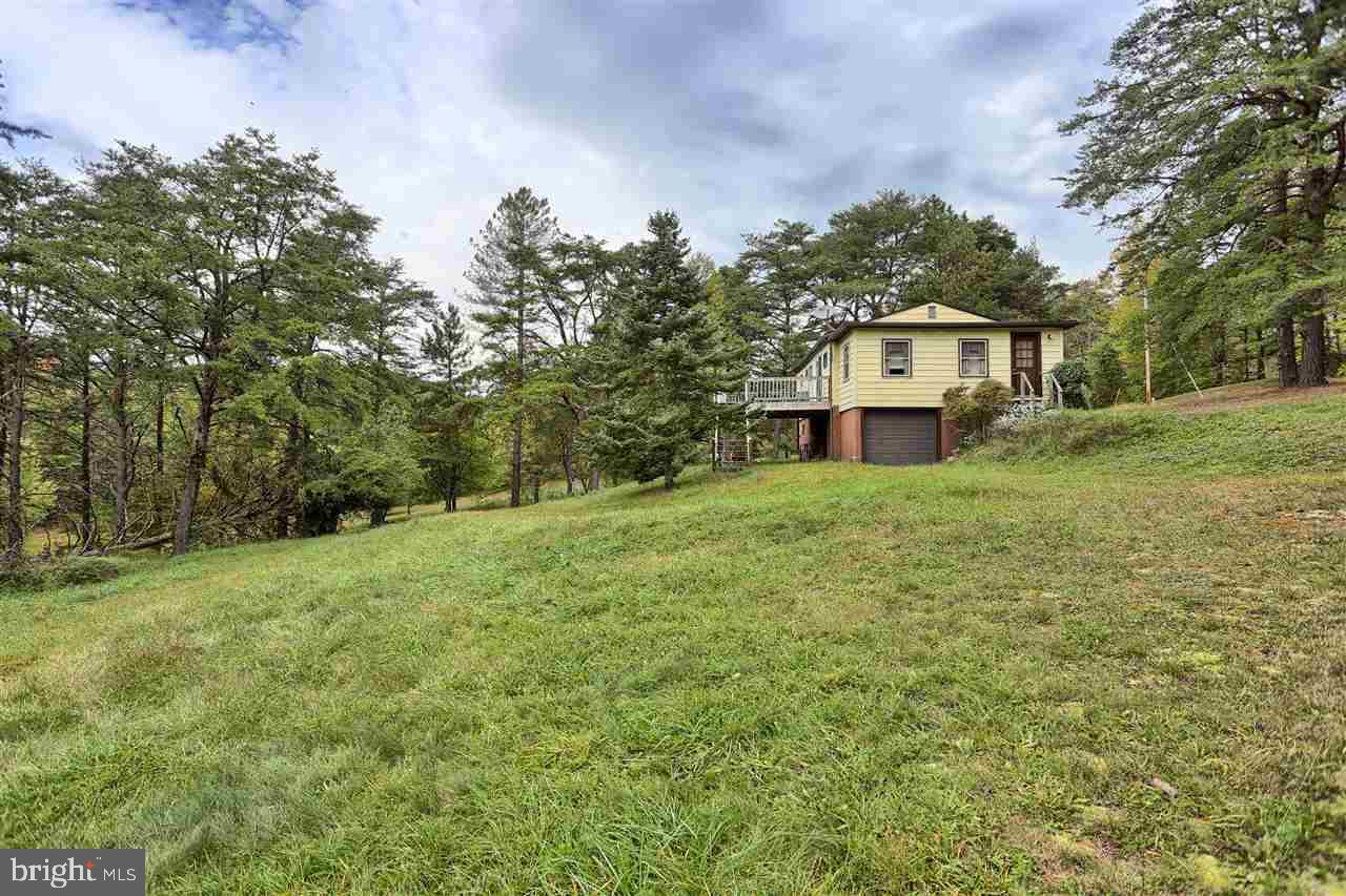 Welcome to Raystown Lake! This cabin sits only 5 miles from the resort entrance. Situated on 1.99 acres & has spring-fed pond. Perfect for the hunting retreat or that weekend getaway. Home offers over 2,500 SqFt of living space, 2 BR's and full BA w/finished porch as 3rd bedroom. Fully equipped kitchen w/all appliances. Finished walk out basement w/laundry room, bar, great room & full bath. One car garage & work room perfect for your storage needs. Get this, before it's gone! Won't last long at $119,900!