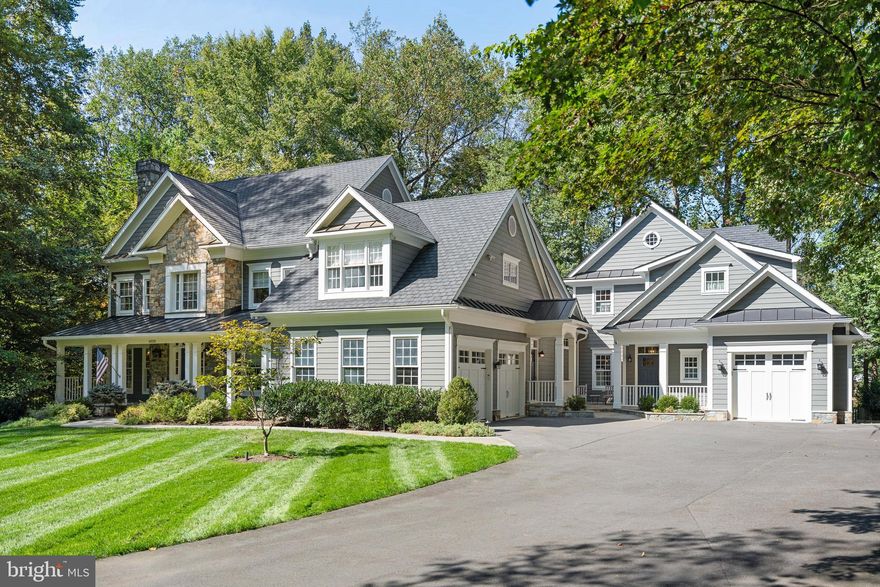 Positioned on a secluded one-acre lot with protected parkland beyond, this meticulously expanded 7,200-square-foot McLean residence exemplifies the sophisticated lifestyle sought by discerning clients. The thoughtfully designed home includes a beautifully appointed attached guest residence, offering flexibility for multi-generational living or staff accommodations.

Enter through the welcoming front porch into a foyer graced by a sweeping curved staircase. The formal living room captivates with floor-to-ceiling windows and a wood-burning fireplace, and the generous dining room flows to a custom butler's pantry featuring beverage refrigeration and abundant storage.

The heart of the home centers on a designer kitchen that balances luxury with livability. Premium appliances, walk-in pantry, and casual dining area extend to a wraparound deck overlooking tranquil parkland. The adjacent family room showcases vaulted beamed ceilings, custom built-ins, and a gas fireplace—perfect for both intimate evenings and grand entertaining.

The primary suite is a serene sanctuary with sitting area, dual custom walk-in closets, and a spa-inspired bath featuring intricate tilework, Palladian window, soaking tub, and oversized shower. Additional accommodations include a secondary suite with updated bath and two additional bedrooms sharing a well-appointed bath.

The walk-out lower level transforms leisure into luxury with home cinema, game room, fitness area, and wet bar crowned by hammered metal ceiling. French doors open to a stone terrace with built-in fire pit, extending entertainment outdoors.

The attached luxury guest house represents true sophistication in secondary living. Complete with private living area, garage access, designer kitchen and bath, walk-in closet, and laundry facilities, it provides the perfect solution for extended family, guests, or household staff.

Minutes from Chain Bridge and George Washington Parkway, this home delivers the ultimate Washington lifestyle: complete privacy on a wooded acre with effortless access to the capital's finest amenities.