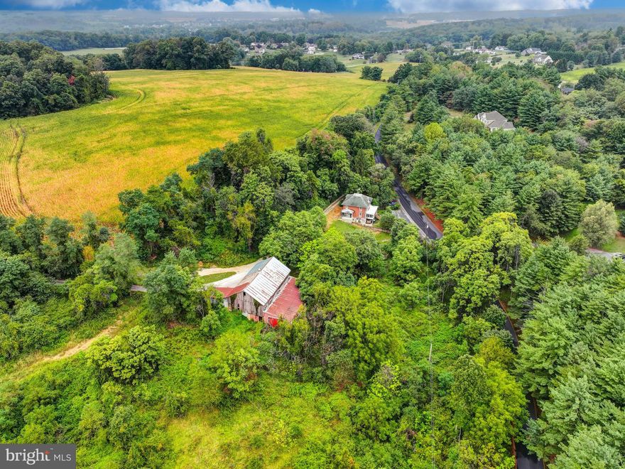 Live authentically. Positioned on nearly five acres of mature greenery and natural privacy, this quintessential two-story brick Farmette carries the gentle romance of years past. Soaring trees and lush foliage frame the home, creating a natural sanctuary of privacy and calm. A grassy front yard and potted plantings lead to an enclosed porch that spans the façade... a perfect perch for taking in the pastoral views. Indoors, a dining nook invites lingering over simple pleasures, while the home itself radiates warmth, character, and a lived-in charm. A charming, classic red barn awaiting renewal. Endless potential... whether refined restoration or a visionary new build, an opportunity to imprint your aesthetic upon a true country retreat. Cultivate your existence. The art of uniting human and home.