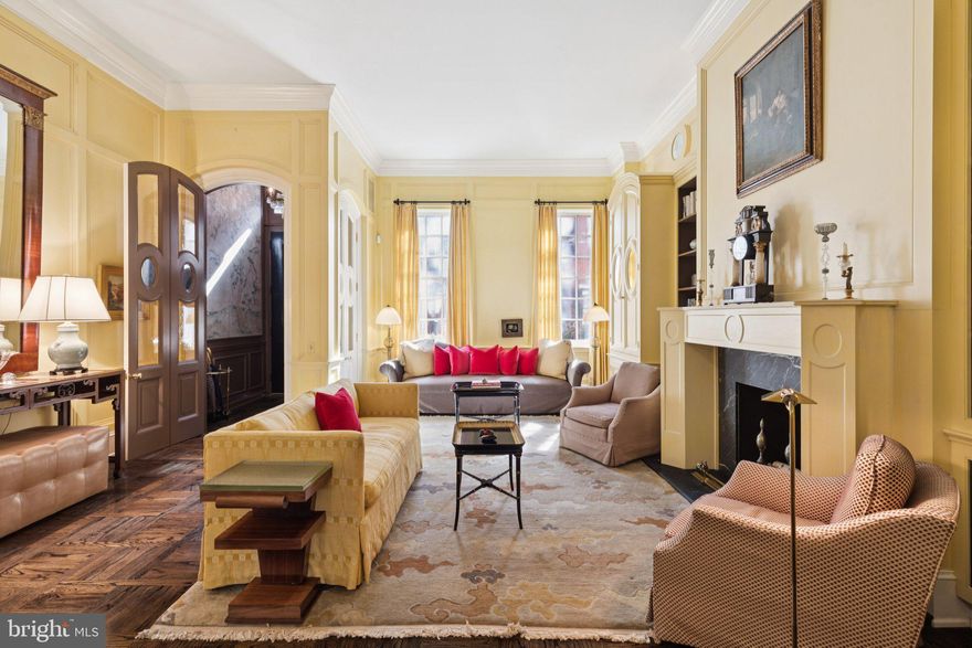 On the most coveted block of Delancey Place, this distinguished 20-foot-wide historic townhome offers over 4,500 square feet, a private garden terrace, elevator access, and the rare luxury of a two-car garage just steps from Rittenhouse Square. Welcome to 1811 Delancey Place, a remarkable Federal Revival residence set along one of Philadelphia’s most picturesque residential streets.

Dating to the 1850s, this elegant five-plus bedroom, four-and-a-half-bath home captures the character of classic Philadelphia architecture while offering generous scale, private outdoor space, and exceptional amenities rarely found in this coveted neighborhood.

Through the entry vestibule, the home opens to a gracious formal living room where historic craftsmanship immediately reveals itself. Rich hardwood floors, classic wainscoting, crown molding, and chair rails frame the space, while a centered marble wood-burning fireplace with built-in shelving and custom armoires creates a stately focal point. A conveniently located powder room serves this level.

A short run of marble steps leads to the elevated dining and kitchen level. The formal dining room features Venetian plaster walls and generous proportions ideal for entertaining. A striking black-and-white marble gallery floor introduces the fully custom eat-in chef’s kitchen with stone countertops, abundant cabinetry, a generous center island, Sub-Zero refrigerator, electric range, and built-in oven and microwave. Radiant heated floors add an extra layer of comfort, while mullioned glass French doors open to the private stone terrace above the garage—an enchanting outdoor retreat with fountain, latticework, and pergola, perfect for al fresco dining or morning coffee.

A sweeping curved staircase ascends to the bedroom levels. The second floor is devoted to two spacious suites at the front and rear of the home. The front primary suite offers a dressing area and marble bath, while the rear suite—currently used as an office and dressing room—includes its own marble bath, elevator access, and a remarkable wall of closets.

Two additional bedroom suites occupy the third floor. The front bedroom features a marble fireplace with decorative mantel, custom built-ins, generous wardrobe storage, and an en-suite bath. At the rear, a large bedroom offers extensive built-in shelving and a private bath with soaking tub and separate glass shower. A full laundry room is conveniently located on this level.

The fourth level provides exceptional flexibility with a spacious front bedroom filled with natural light and a built-in desk. Adjacent is a unique studio or workshop with attic access and a full bath featuring a classic clawfoot tub—ideal as a creative workspace, guest quarters, or potential au pair suite.

The finished lower level offers a welcoming family room or media den with exposed beams and custom built-ins. The attached two-car garage provides exceptional convenience—an extraordinary amenity on this block. An elevator serves three levels of the home for easy access from the garage to the main living areas.

Set mid-block on tree-lined Delancey Place and moments from both Rittenhouse Square and Fitler Square, the home is also close to the restaurants, cafés, and cultural institutions that define Center City living, including the renowned Kimmel Center for the Performing Arts.

Beautifully maintained and reflecting thoughtful renovations completed in 2001, the property offers a rare opportunity to enjoy its classic elegance today or reimagine a truly exceptional residence.