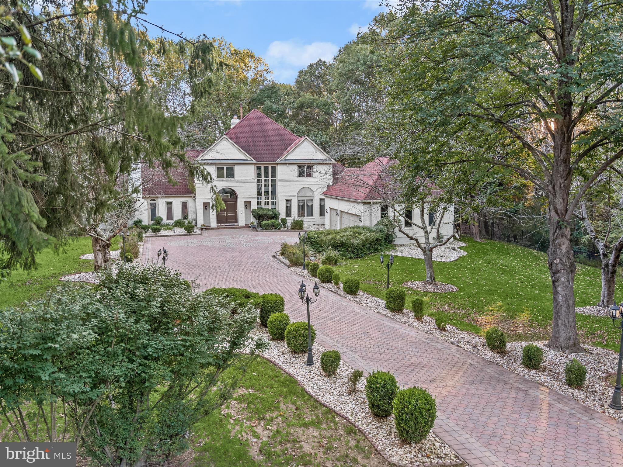 Don’t miss your chance to experience firsthand the unmatched luxury, privacy, and resort-style living this exceptional Potomac estate offers. Tucked away at the end of a quiet cul-de-sac on over two private acres, this remarkable Potomac estate offers a rare blend of refined luxury, thoughtful design, and enduring personal legacy. Once home to a highly successful and well-known entrepreneur, the residence reflects a lifestyle defined by achievement, sophistication, and purpose. Spanning more than 9,000 square feet, this stately residence has been meticulously upgraded with over $700,000 in enhancements, blending timeless architecture with resort-style living. From the heated outdoor pool with cascading fountain to the professionally designed wine cellar and cigar room, every space is tailored for both grand entertaining and serene retreat. A handsome brick exterior welcomes you, framed by lush pear trees lining a paver driveway with a custom rose-petal inlay. The side-loading three-car garage features epoxy flooring and provides ample space for vehicles and storage. Inside, the home’s grand entrance opens to a formal living room with a dramatic floor-to-ceiling garden window, filling the space with natural light and offering an immersive view of the surrounding forested landscape. It’s the perfect place to unwind while soaking in the tranquil beauty of nature from the comfort of your own home. The gourmet kitchen is a chef’s dream, outfitted with granite countertops, premium stainless steel appliances, and a sunny breakfast area. Deck access from the kitchen makes outdoor dining and summer entertaining seamless. The main-level primary suite is a private retreat, offering direct access to the deck with views of the pool. The spa-inspired bath features Carrara marble, quartz vanities, and a sleek glass-and-marble shower with multiple jets. Just off the foyer, a stately study with built-in bookcases and fireplace provides the perfect space to work or unwind. Upstairs, four spacious bedrooms offer comfort and privacy. Two share a luxurious bath with Acqua marble tile and a quartz-topped vanity, while the others are served by a serene bathroom with beige marble and a unique forest-themed shower. The walkout lower level is a true showstopper. Inspired by Miami’s Hakkasan, the commercial-grade bar dazzles with white quartz, stacked stone, and dramatic lighting. The wine and cigar lounge is a connoisseur’s dream, featuring a cedar ceiling, mahogany racks, dual wine chillers, a 1,000-cigar humidor, Italian cabinetry, stone walls, custom furniture, and wine-proof porcelain flooring - all served by special ventilation for a premium experience. Outside, the home features three levels of patios, a tranquil rock garden, and multiple entertaining areas that connect effortlessly with the lower-level kitchen. A built-in gas line makes grilling a breeze, and the wooded setting offers rare seclusion and peace. Additionally, this home is zoned for highly-rated schools including Winston Churchill High a historic Blue Ribbon school. Lovingly maintained for over two decades, this one-of-a-kind home is both an entertainer’s dream and a private sanctuary, blending timeless style, luxury amenities, and a legacy of success, all set on one of Potomac’s most sought-after lots.