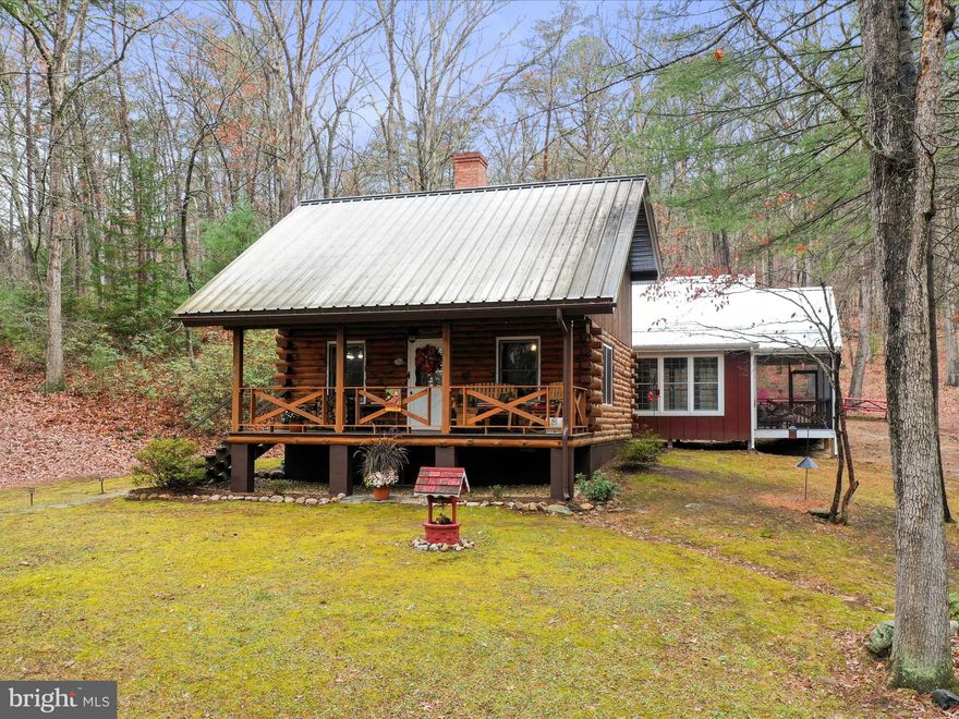 This delightful 3-bedroom, 2-bathroom log cabin is in pristine condition and boasts a thoughtfully renovated addition with charming board and batten siding. The spacious primary bedroom features a generous walk-in closet and a screened-in porch, offering a peaceful retreat. Plus, the home is equipped with high-speed fiber optic internet for seamless connectivity.

Inside, the kitchen and bathrooms have been tastefully updated to enhance the cabin’s rustic character. The primary bathroom is completely new, featuring a stylish tiled shower for a modern touch. Custom cabinetry, quartz countertops, and modern stainless steel appliances elevate the kitchen while preserving the space's warmth. The guest bathroom is highlighted by a beautifully restored clawfoot tub. Practical updates include a tankless water heater and a ventless dryer, ensuring efficiency and convenience. A blend of original hardwood floors and contemporary tile throughout the home creates an appealing balance of classic charm and modern style. Two additional bedrooms are located on the upper level.

The property spans 18 unrestricted acres, offering privacy and space, with a private driveway and a two-car detached garage. Spring-fed pond on the property. Just a 5-minute drive from Wardensville, you’ll have easy access to local restaurants, cafes, markets, and shops. For broader amenities, Winchester, VA is under 40 minutes away, and Washington, D.C. is just under two hours.